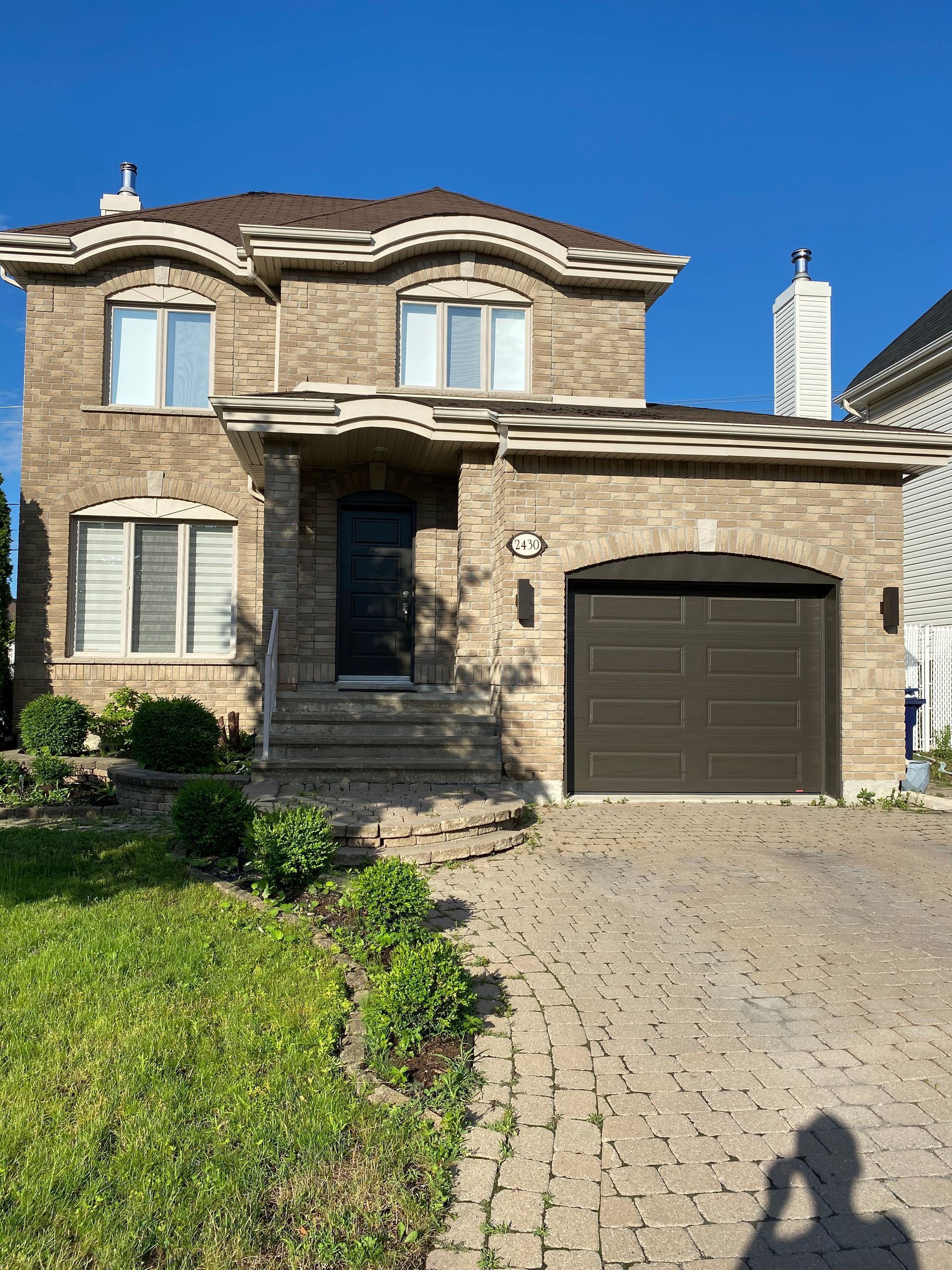 un homme prend une photo d'une maison en brique avec une porte de garage.