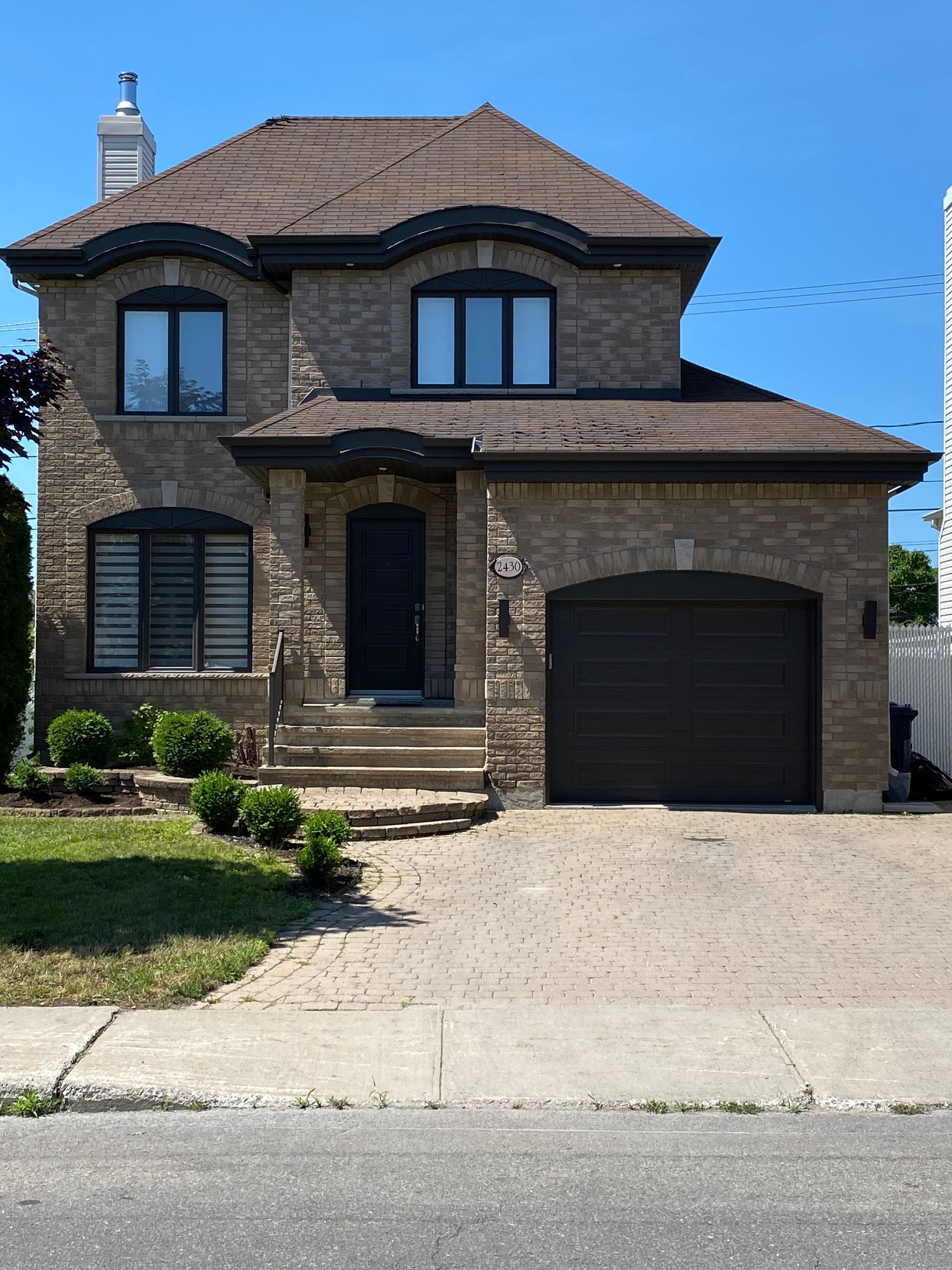 une grande maison en brique avec une porte de garage noire