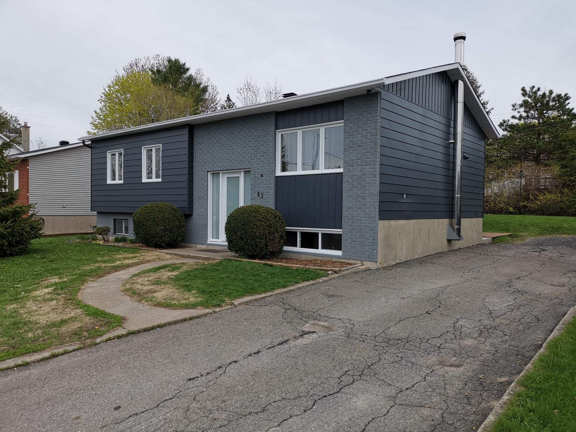 Une maison avec beaucoup de fenêtres et une allée devant.