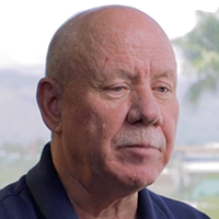 Woman with light brown hair, smiling, wearing a white collared shirt, outdoors on a foggy day.