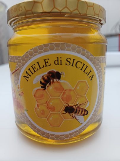 Miele dorato che viene versato in un favo, primo piano con sfondo sfocato.
