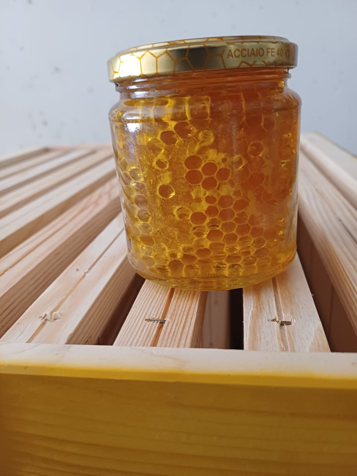 Barattolo di miele dorato su una cornice di legno, illuminato naturalmente.