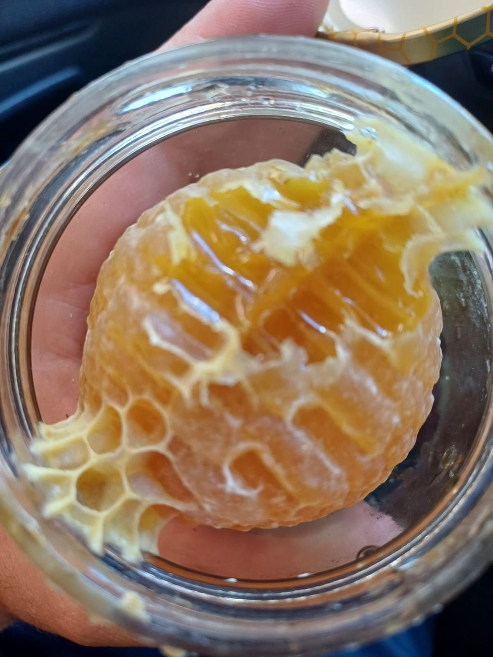Due uomini presso una bancarella di prodotti alimentari siciliani con prodotti dorati. Testo e logo 