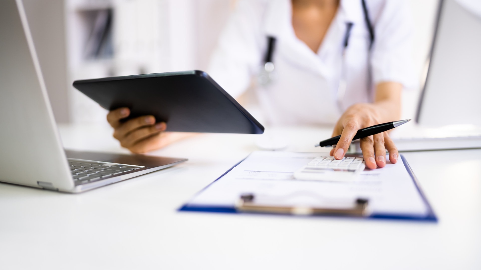 A doctor is using a tablet computer while sitting at a desk.