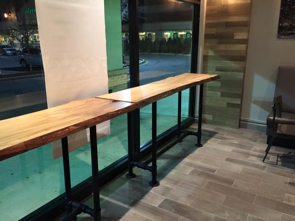 A long wooden table is sitting in front of a window in a room.
