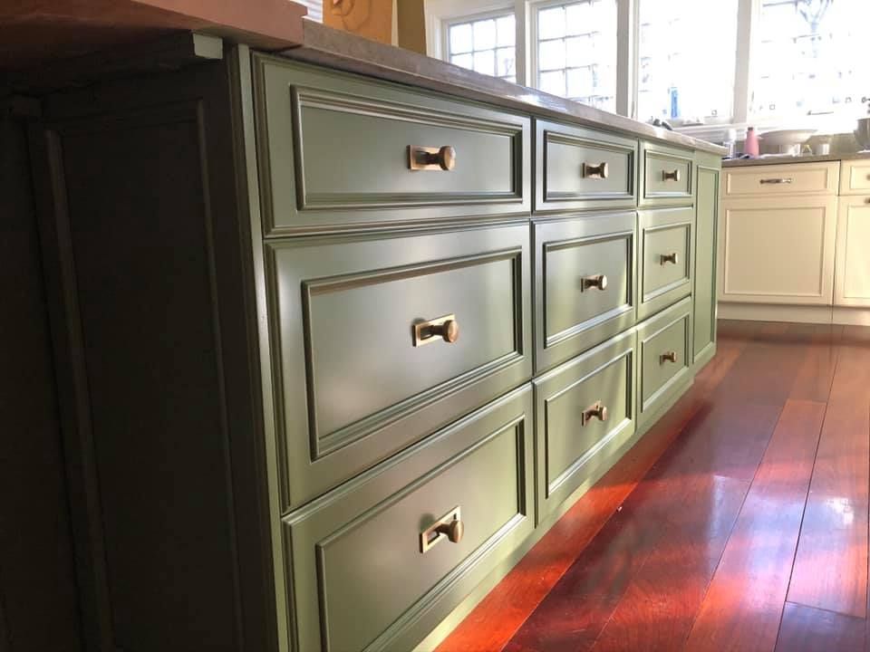 A kitchen with green drawers and white cabinets