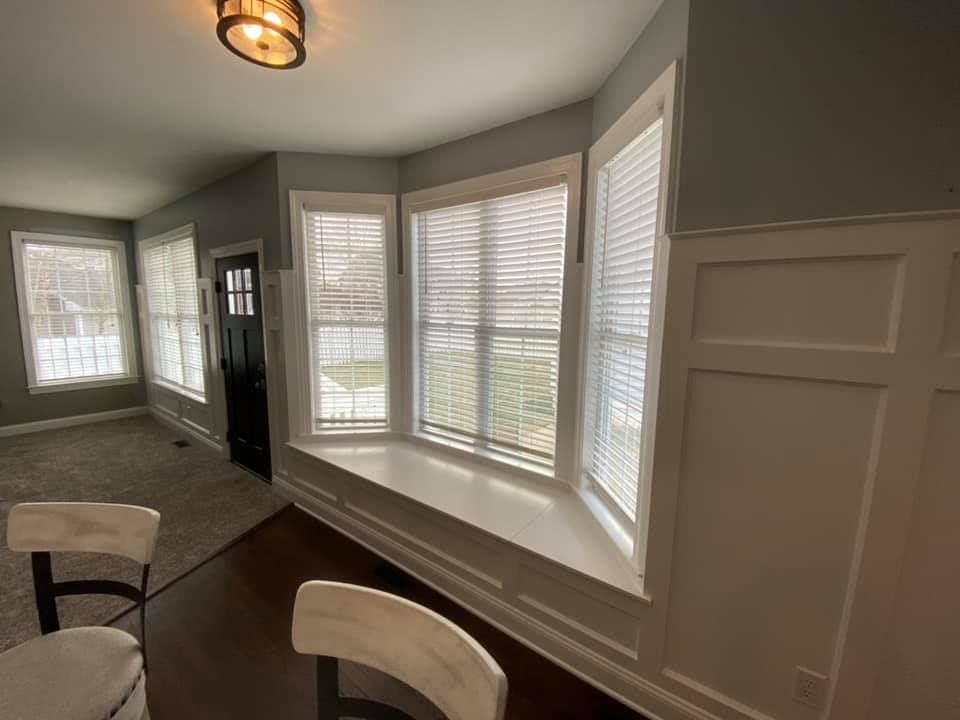 A living room with a lot of windows and a chair.
