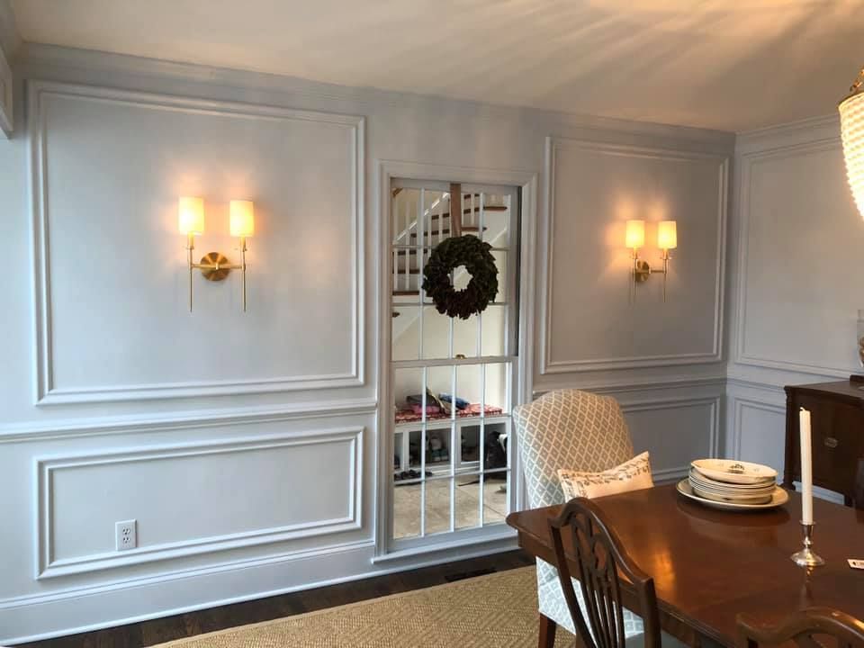 A dining room with a table and chairs and a wreath on the wall.