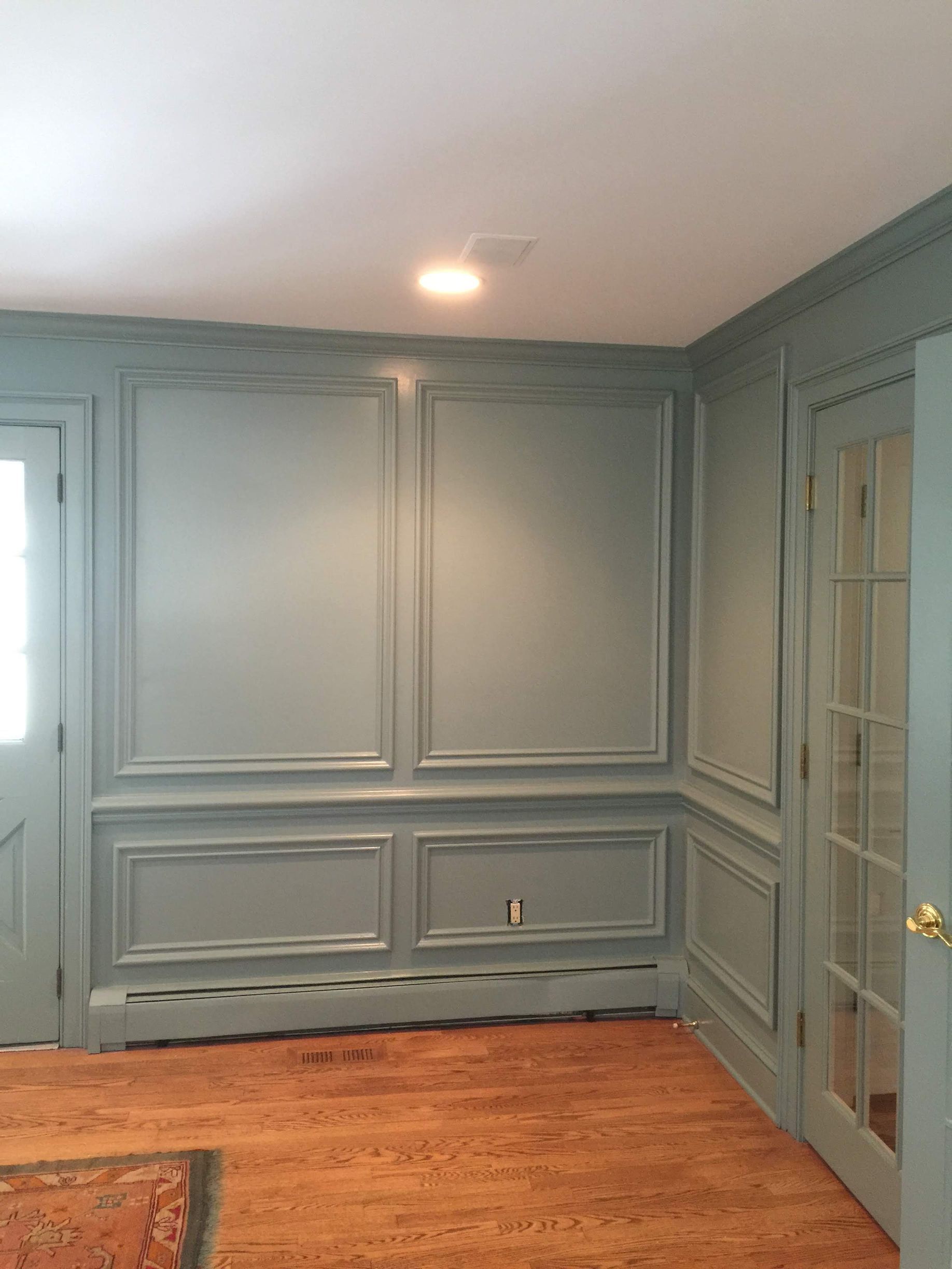 A room with a wooden floor , gray walls , and a door.