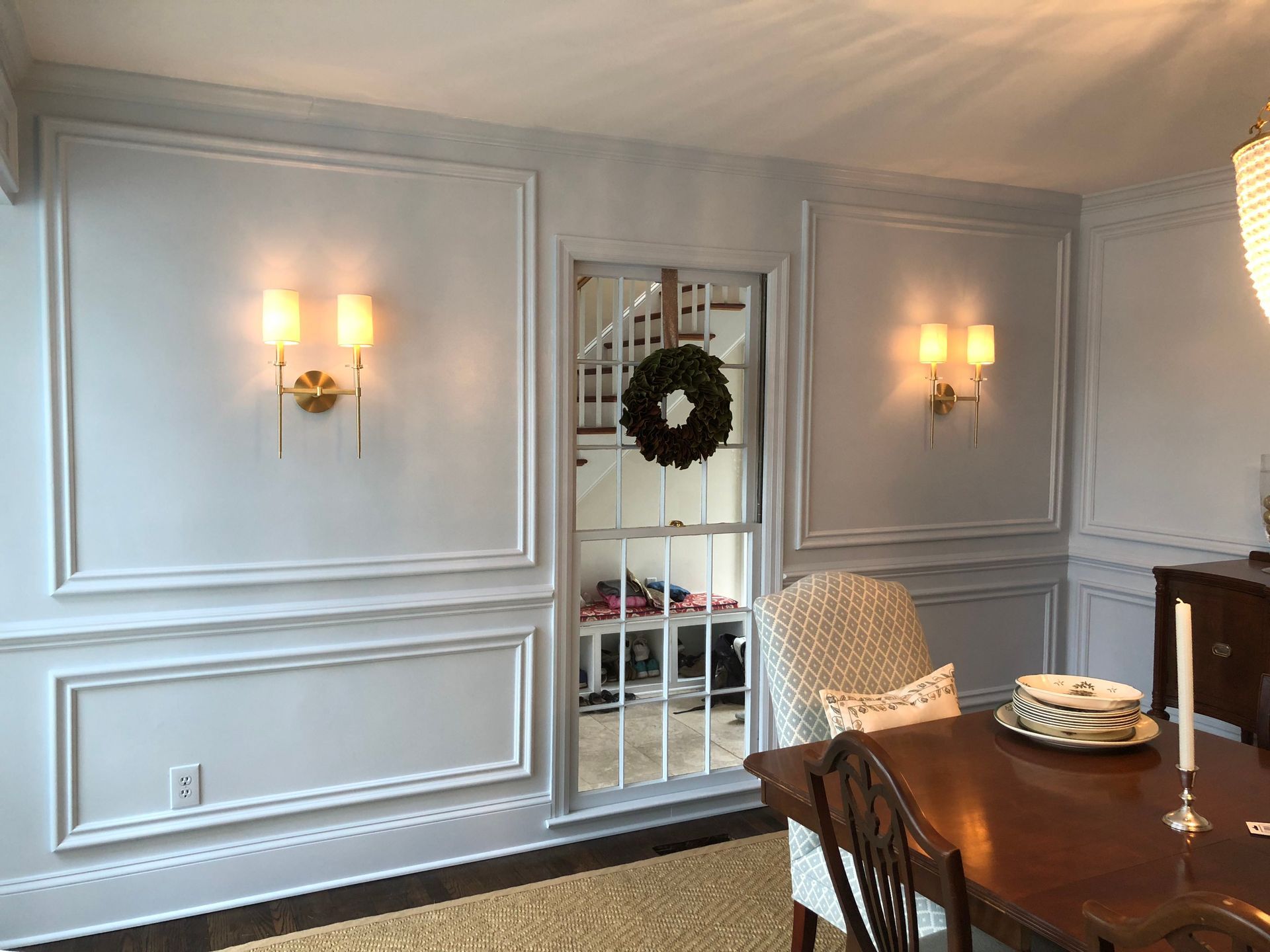 A dining room with a table and chairs and a wreath on the wall.