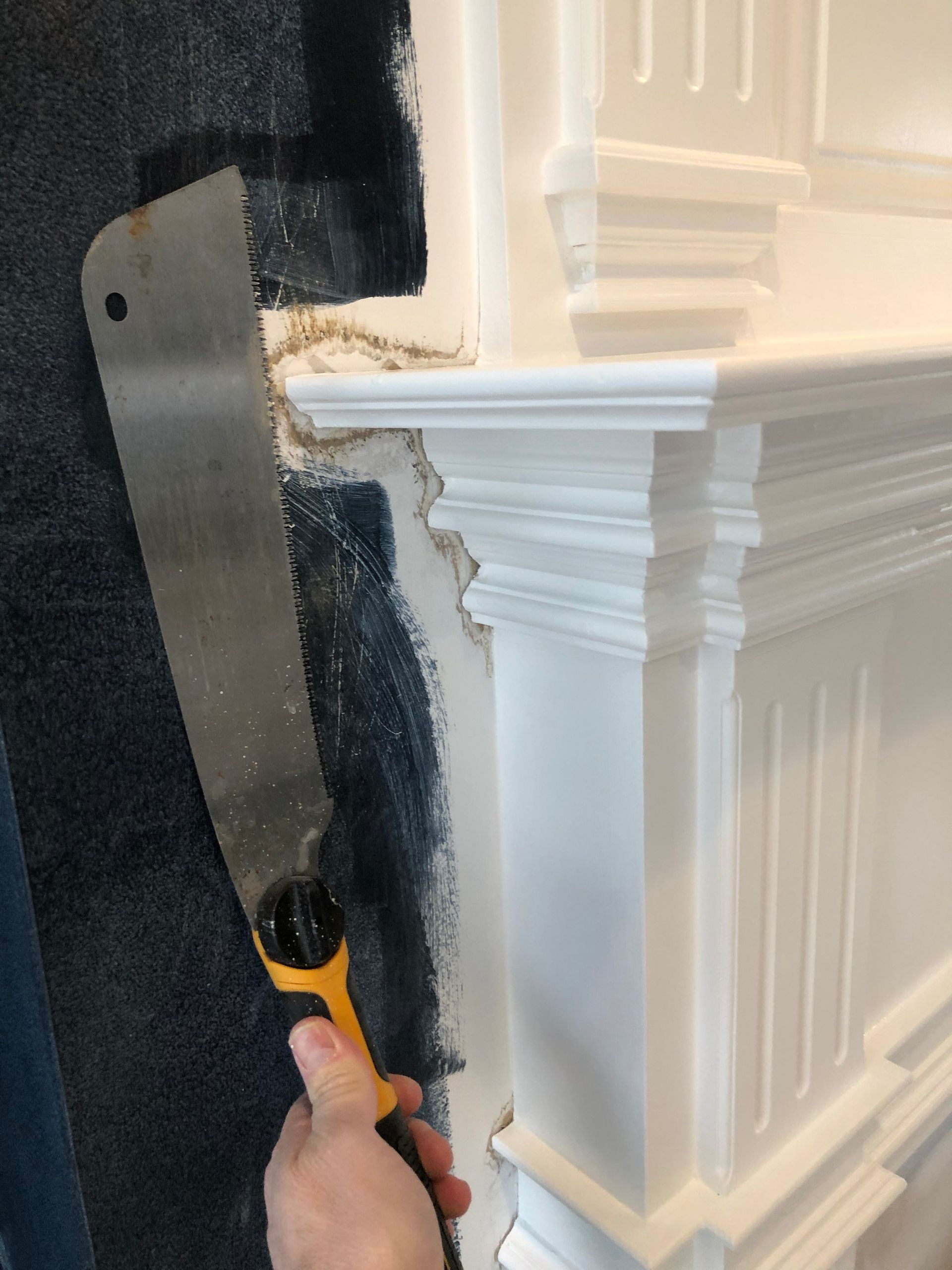 A person is using a saw to cut a hole in a wall