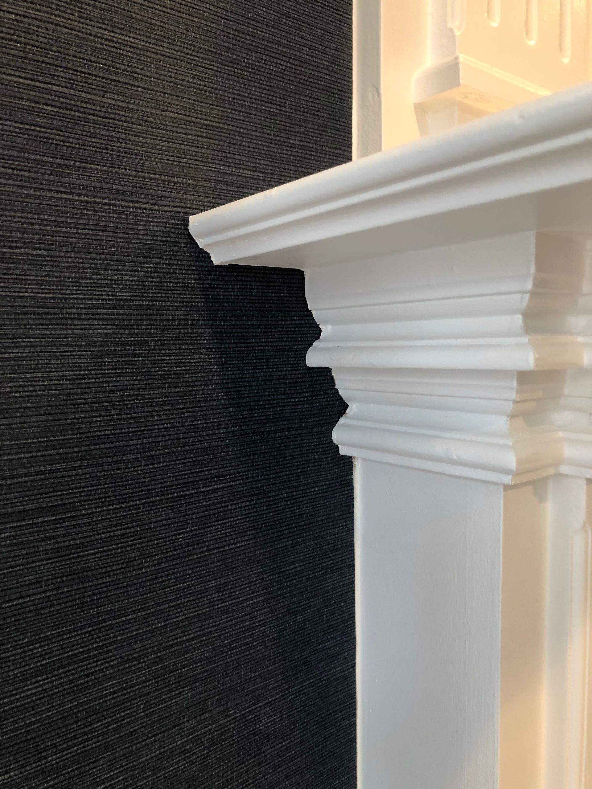 A white fireplace mantle with a black wall behind it.