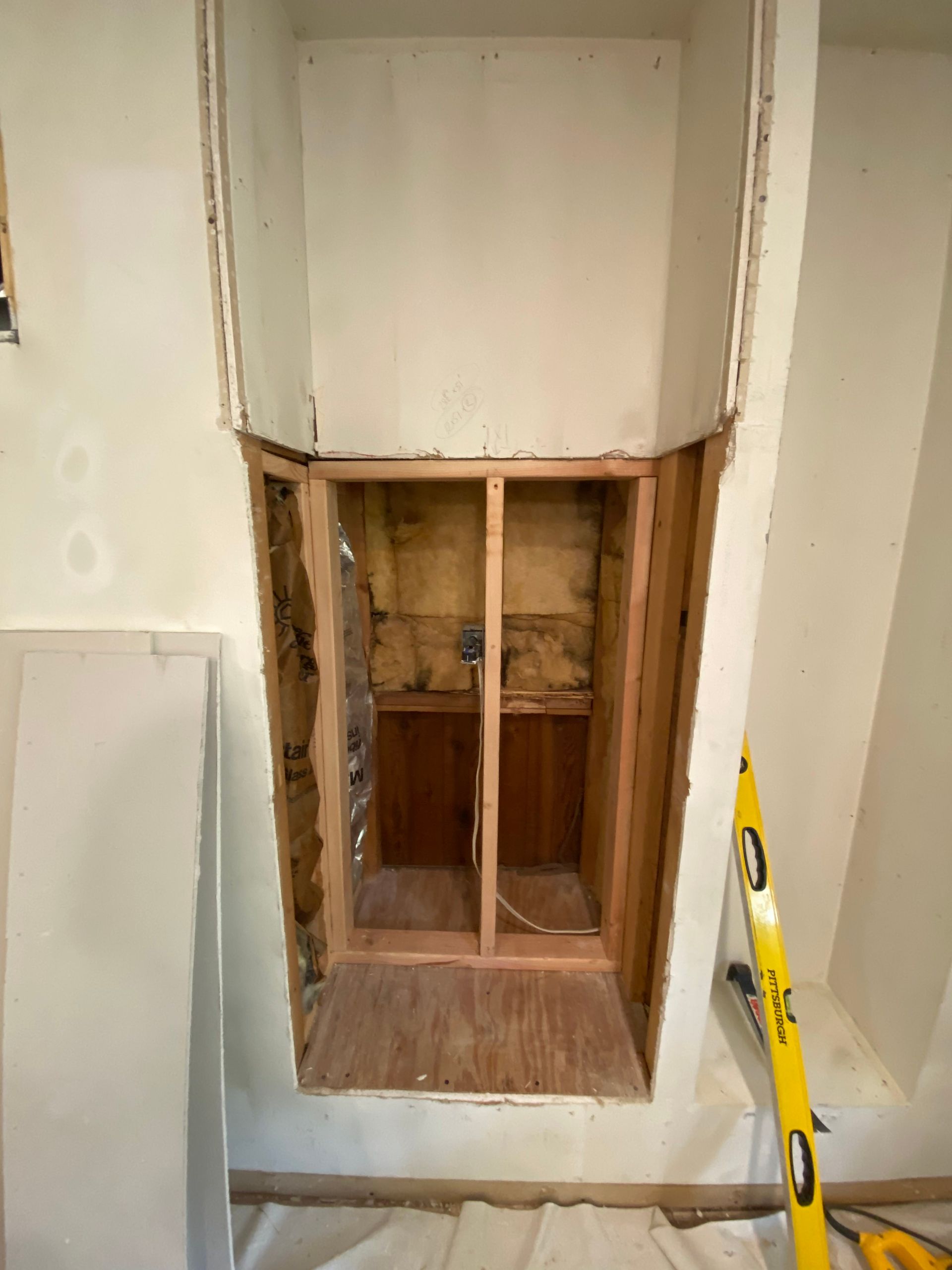 A wooden box is being built into a wall in a room.