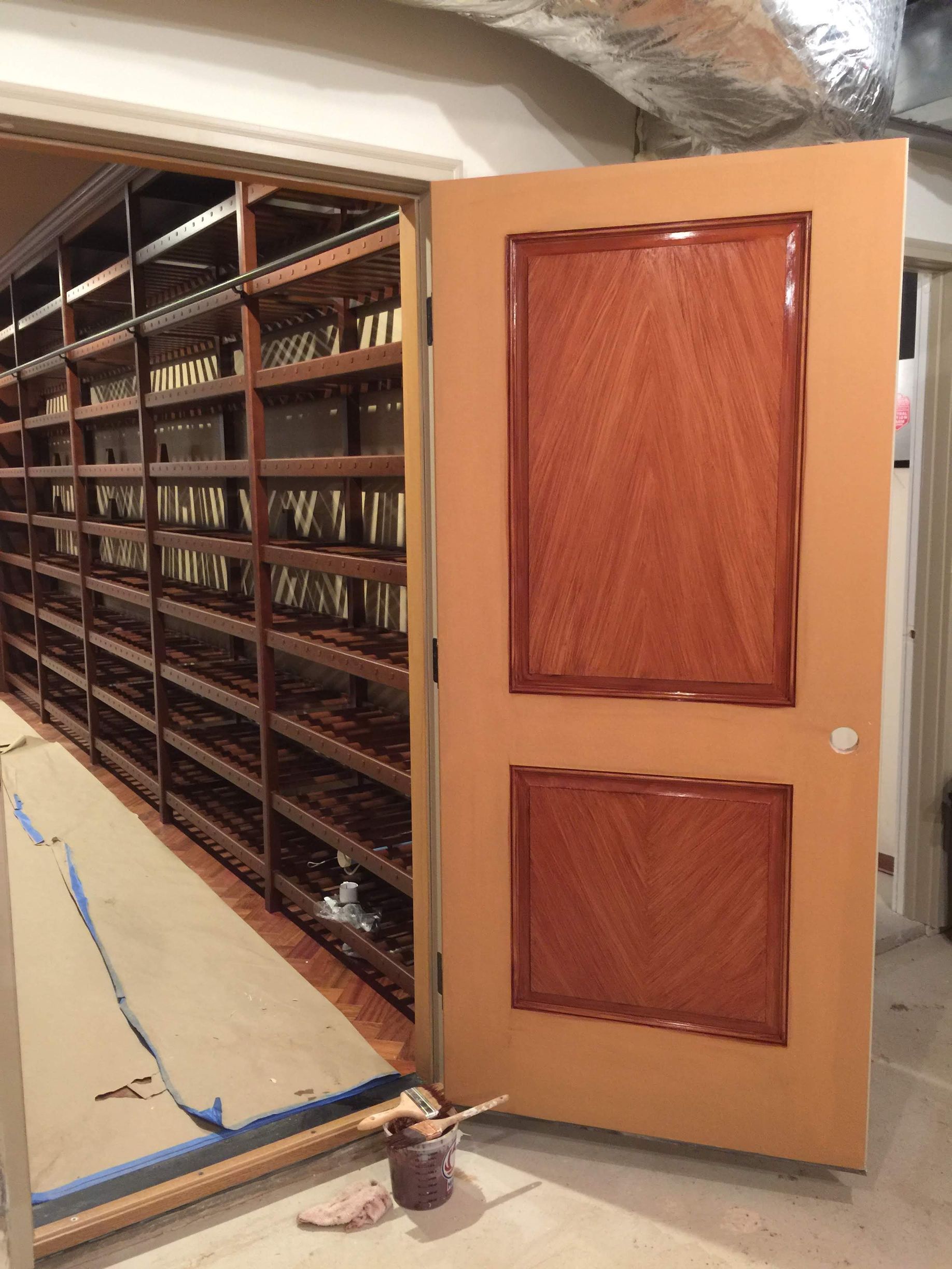 A wooden door is open in a room with shelves.