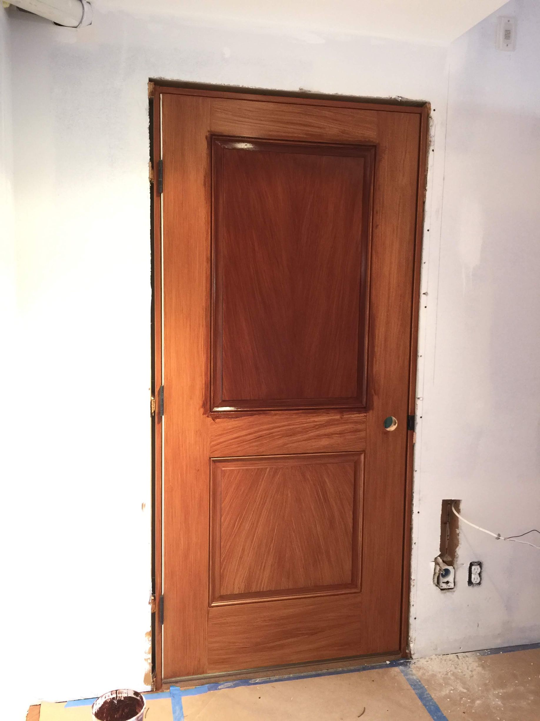 A wooden door in a room with a white wall