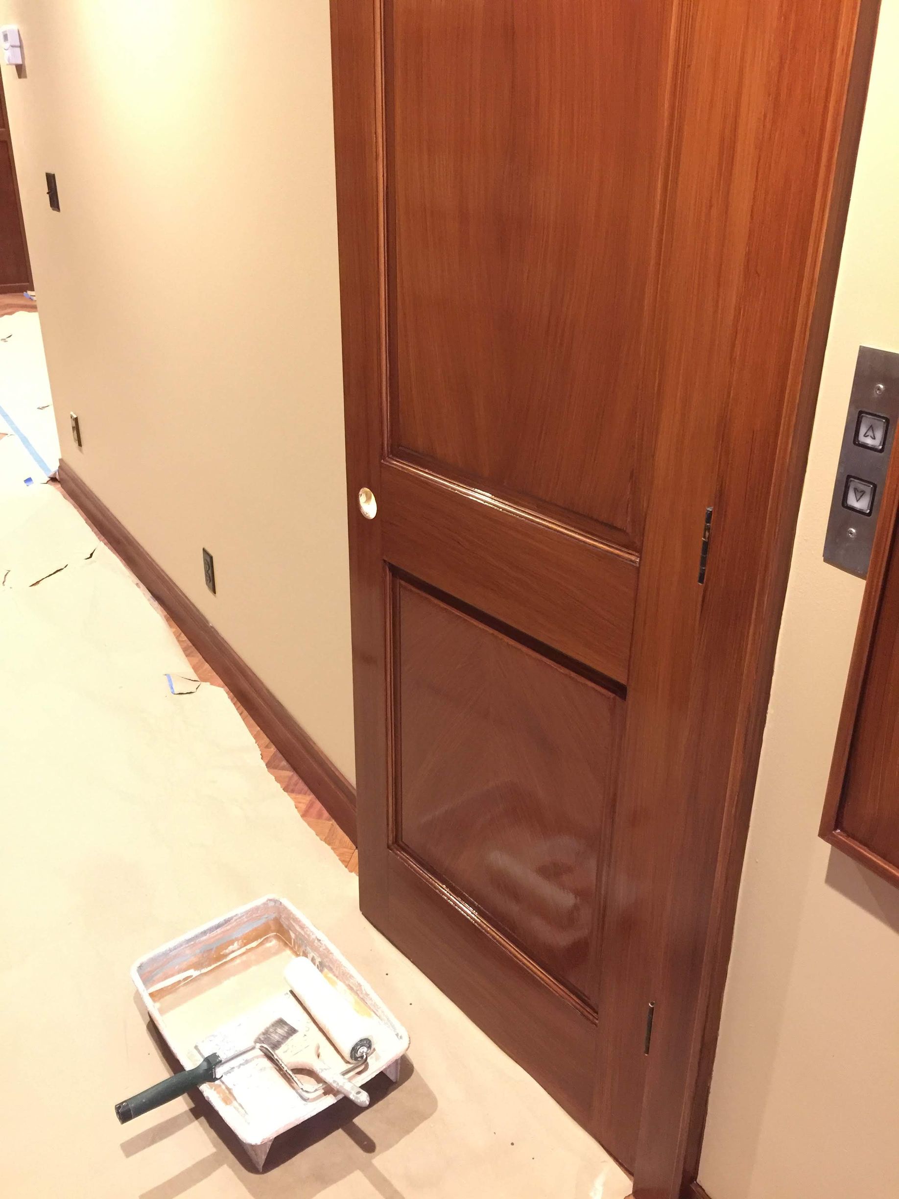 A tray of paint sits on the floor next to a wooden door