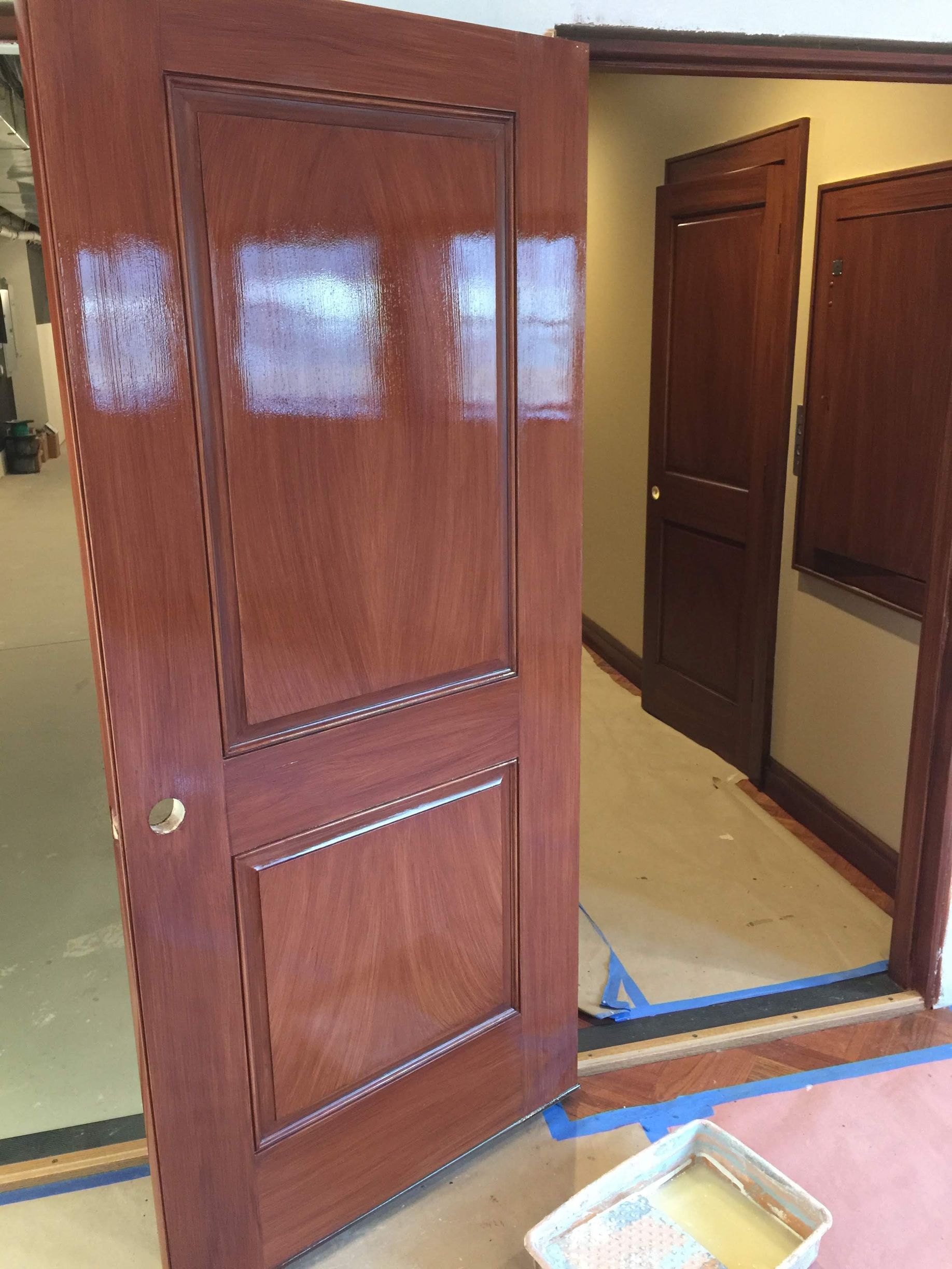 A wooden door is open in a room with a tray of paint on the floor.