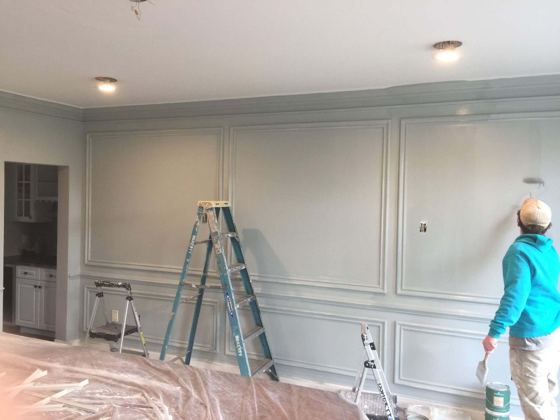 A man is painting a wall in a living room.