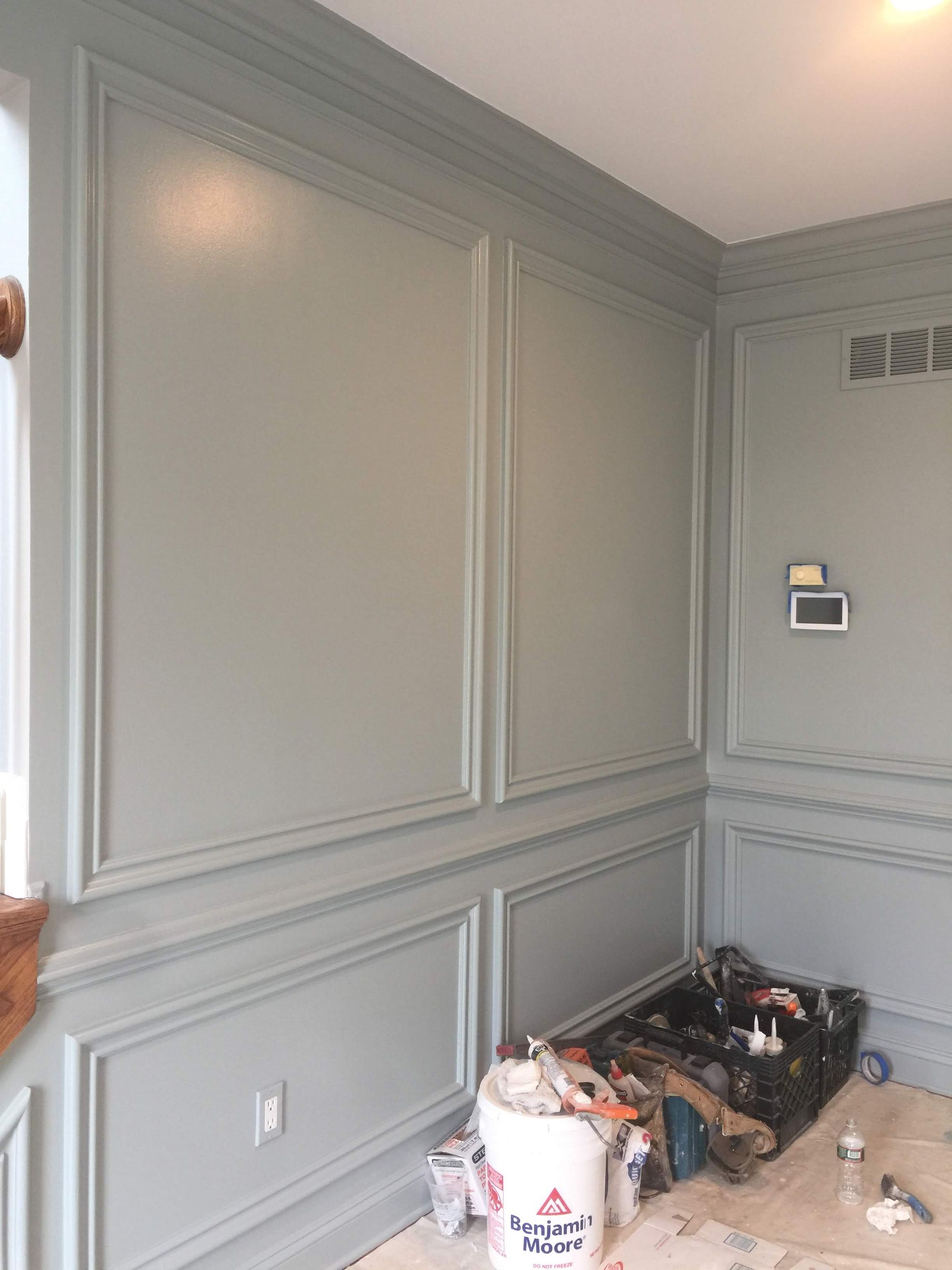 A room with a bucket of paint on the floor and a bucket of paint on the wall.