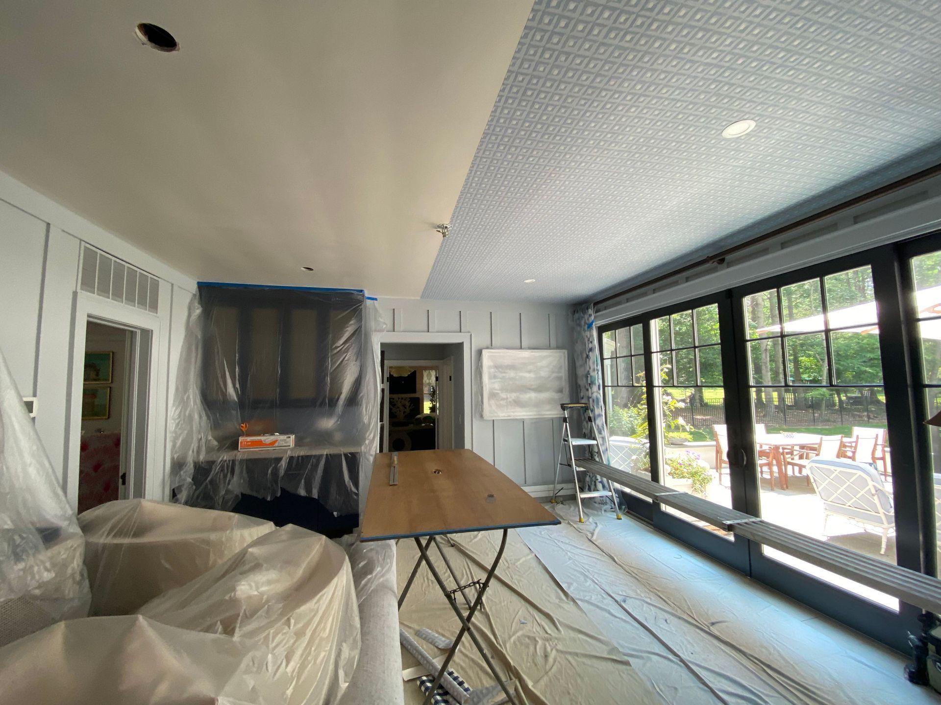 A room with a table and a lot of windows is being painted.