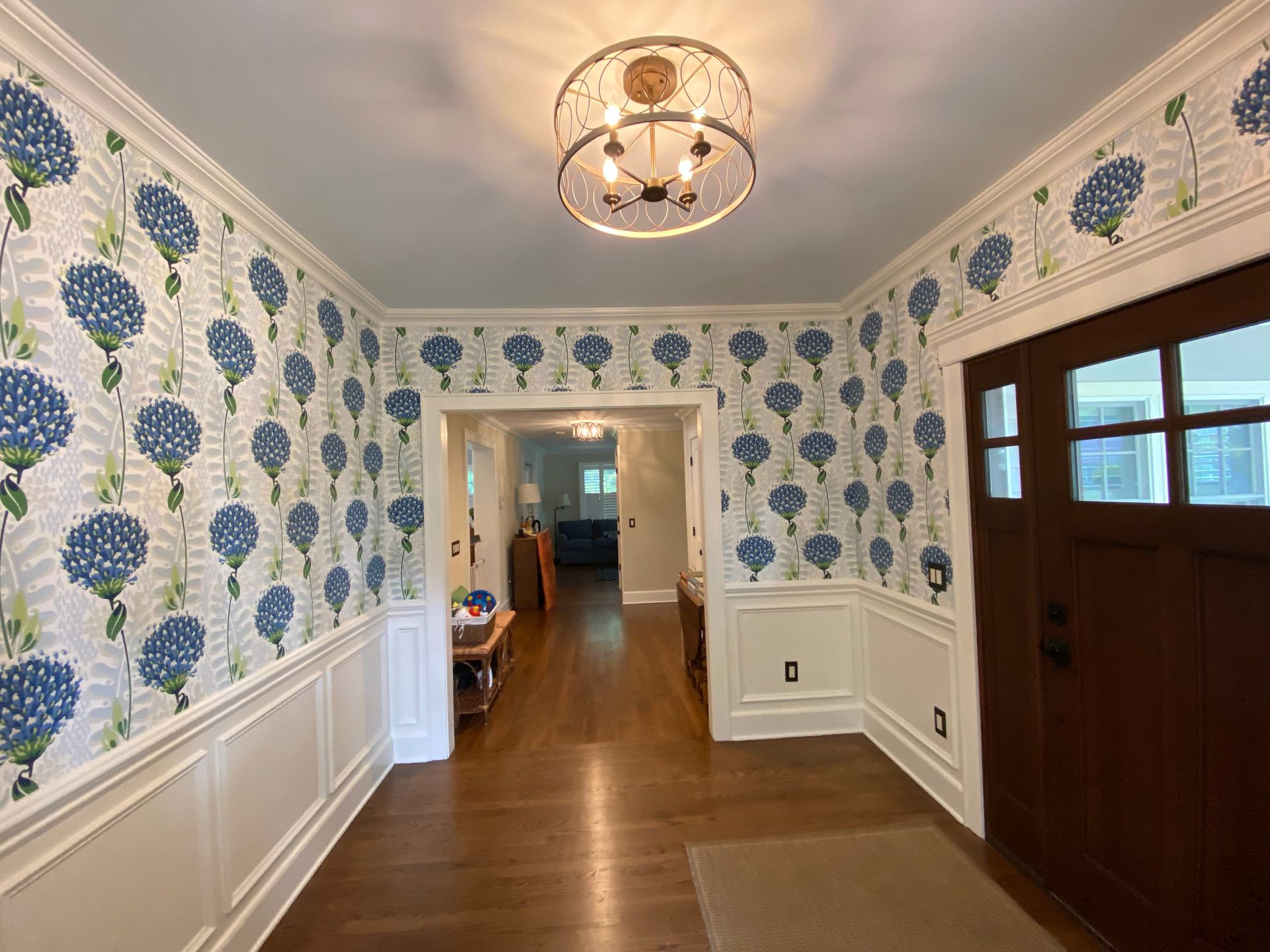 A hallway with blue flowers on the walls and a chandelier.