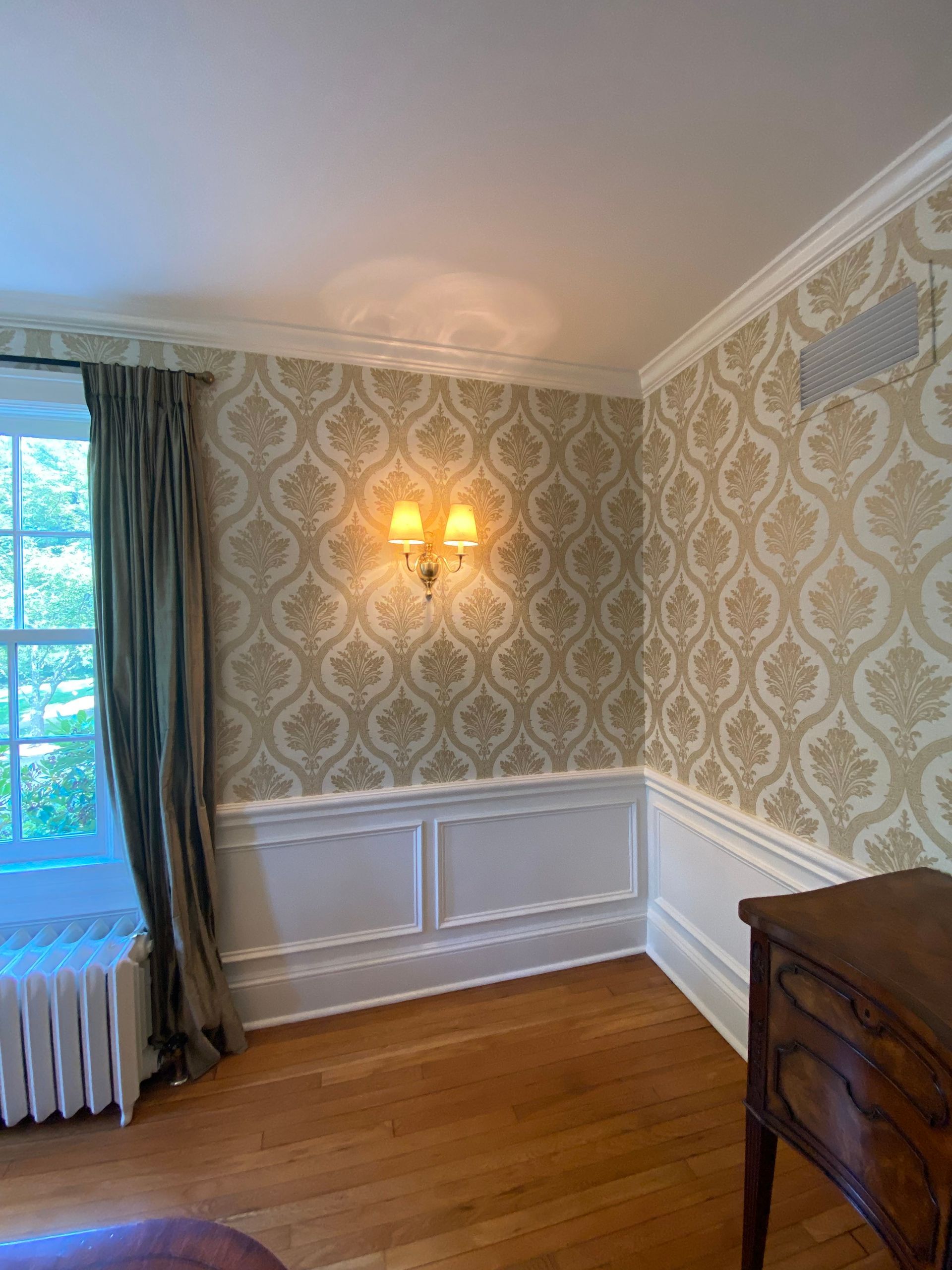 A bedroom with hardwood floors , a dresser , and a window.