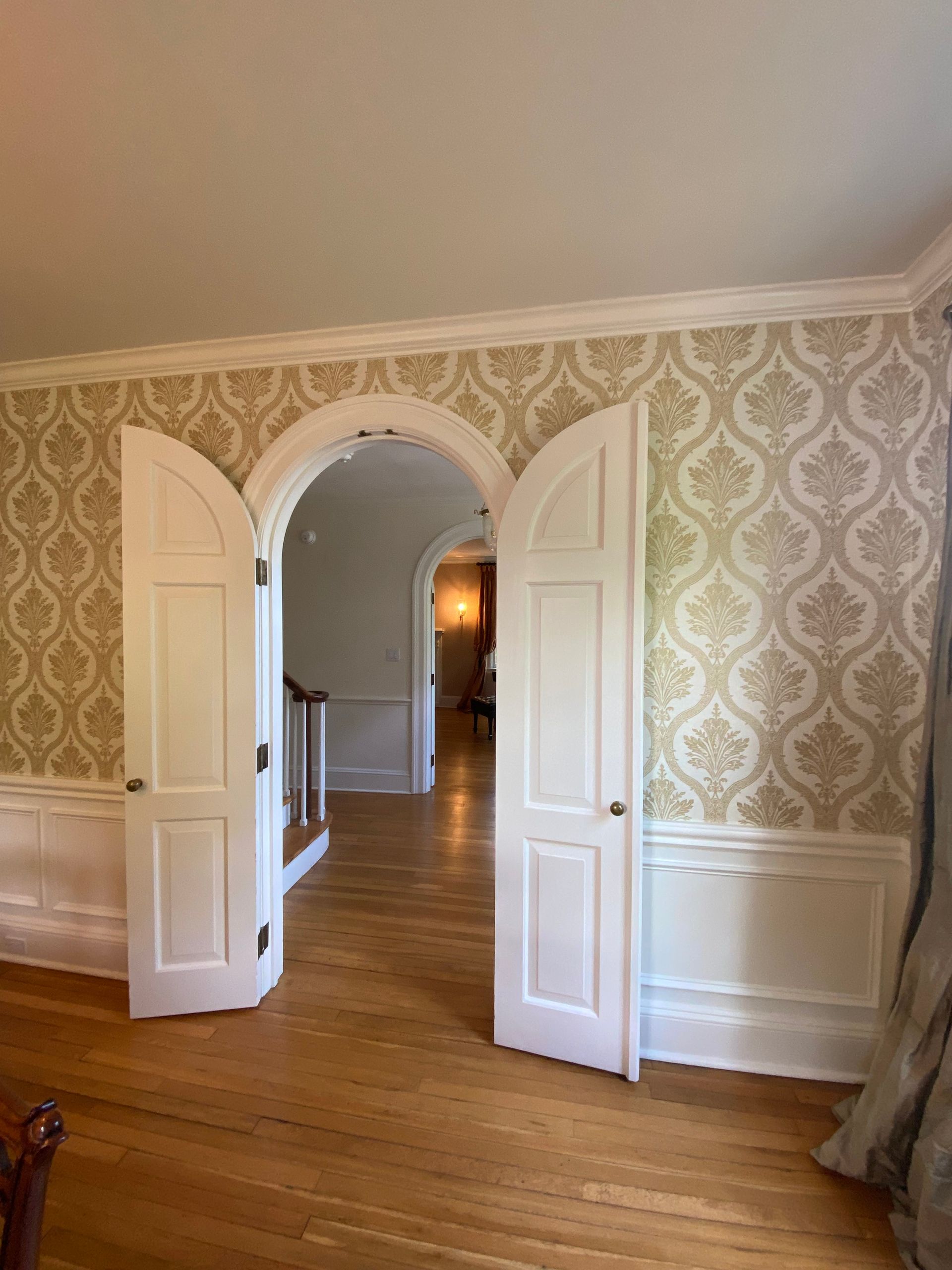 A room with a staircase and a doorway leading to another room.