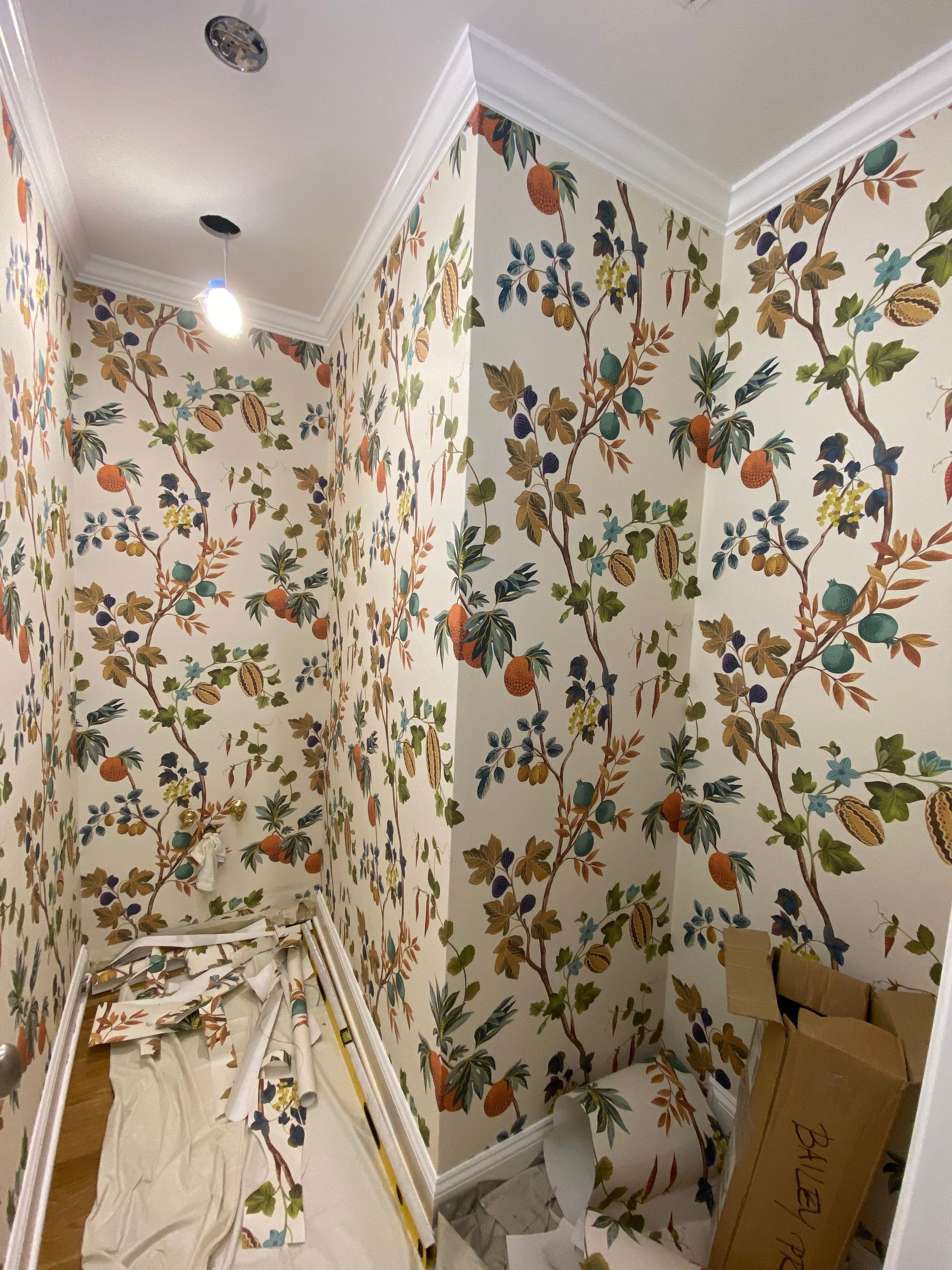A room with a floral wallpaper and a box on the floor.