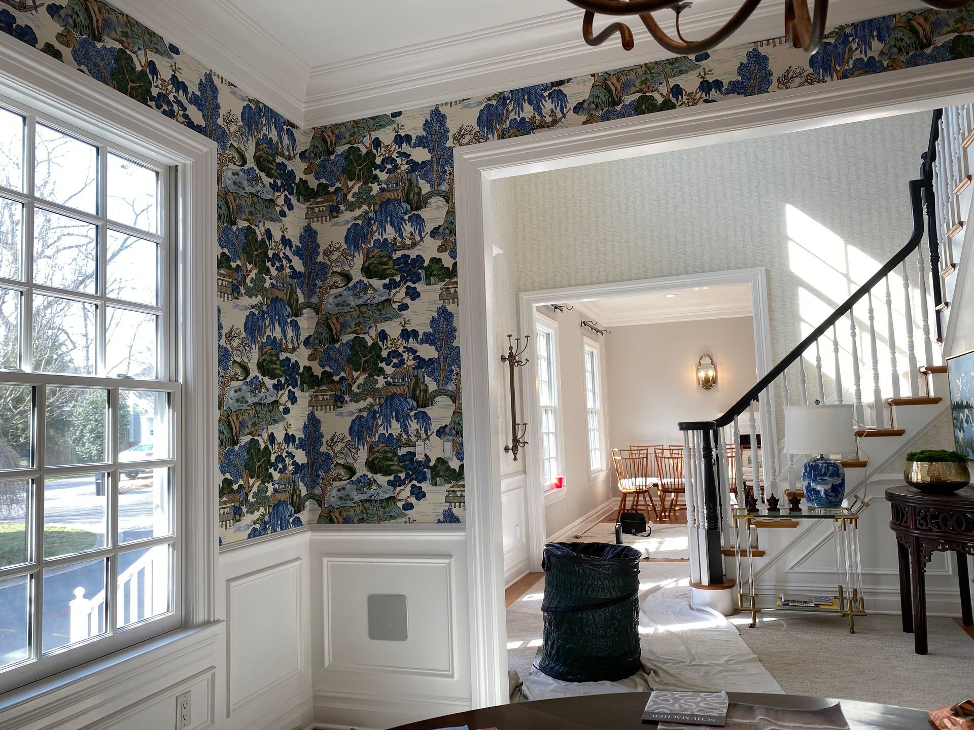 A living room with blue and white floral wallpaper and a staircase