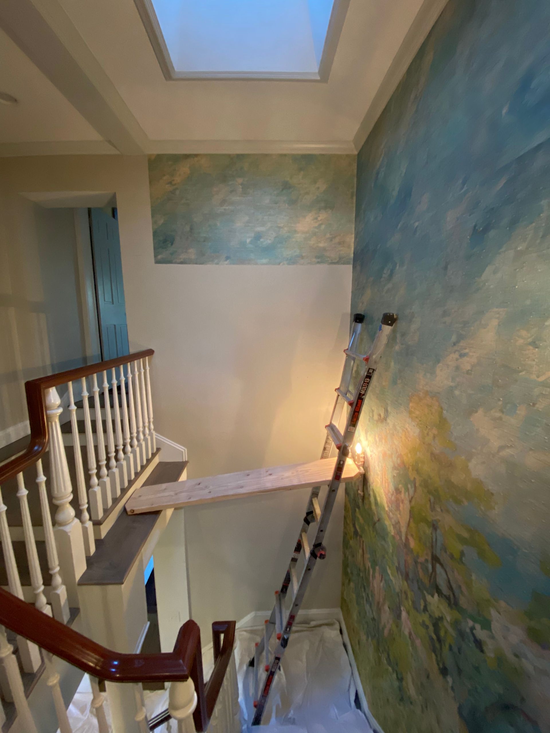 A staircase with a ladder and a painting on the wall.