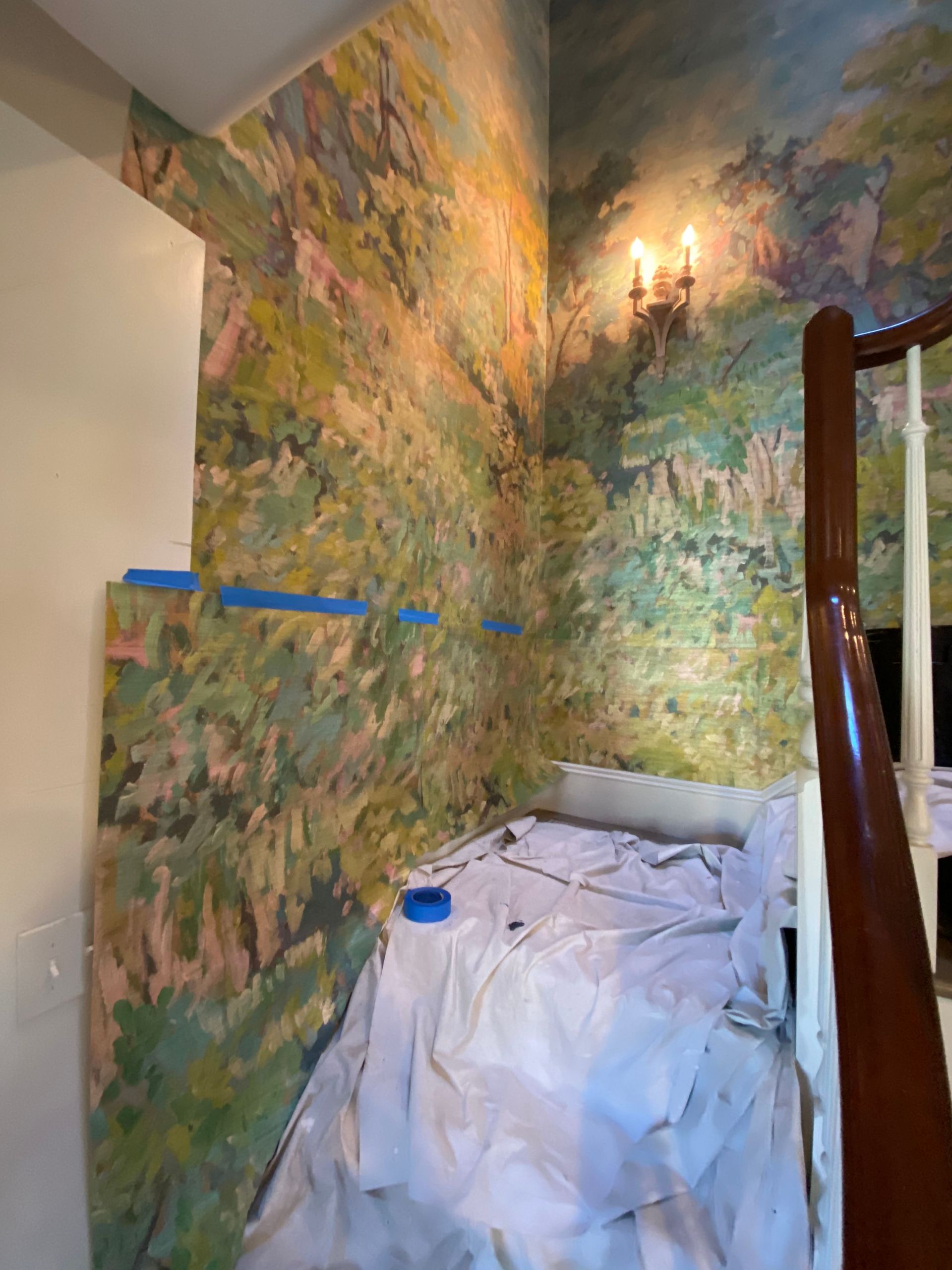 A room with a painting on the wall and a staircase.