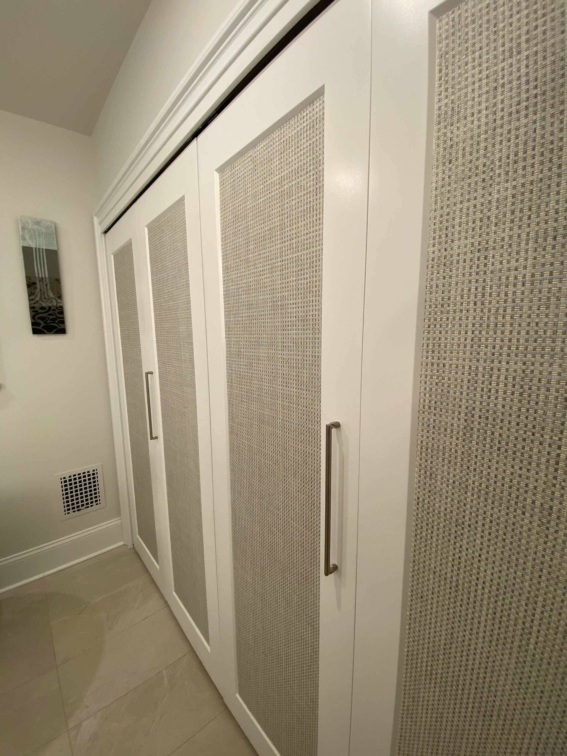 A hallway with white cabinets and a picture on the wall.