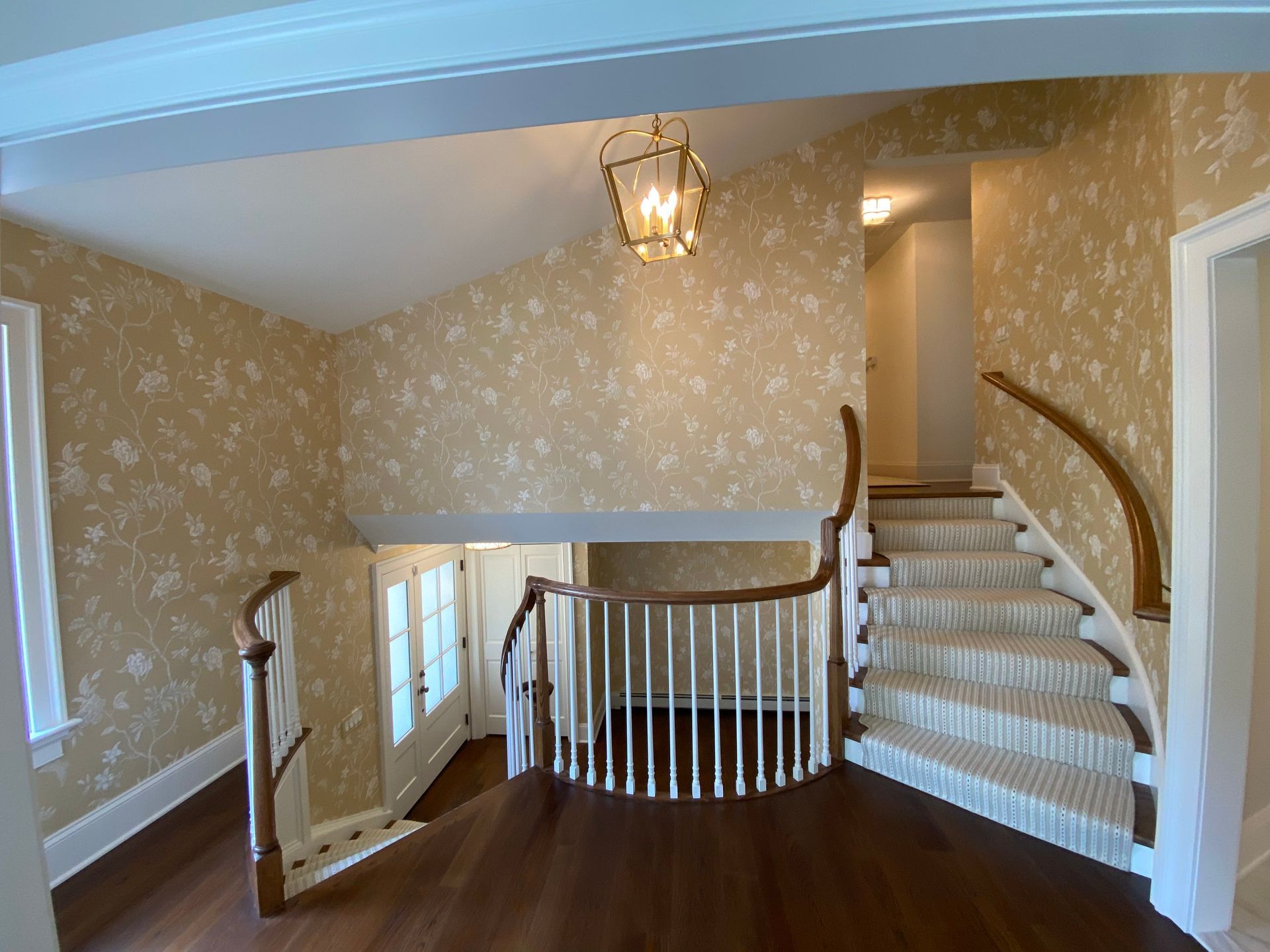 An empty hallway with stairs and a chandelier hanging from the ceiling