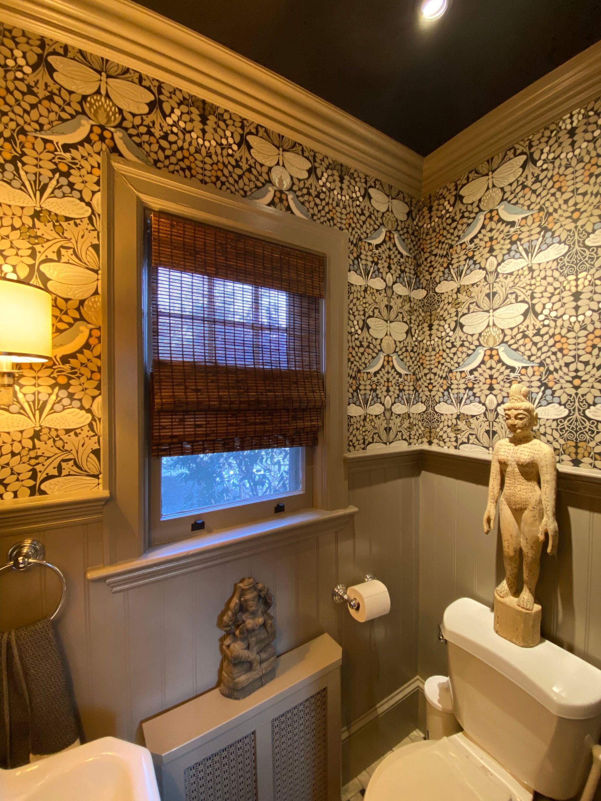 A bathroom with a statue of a woman on the toilet