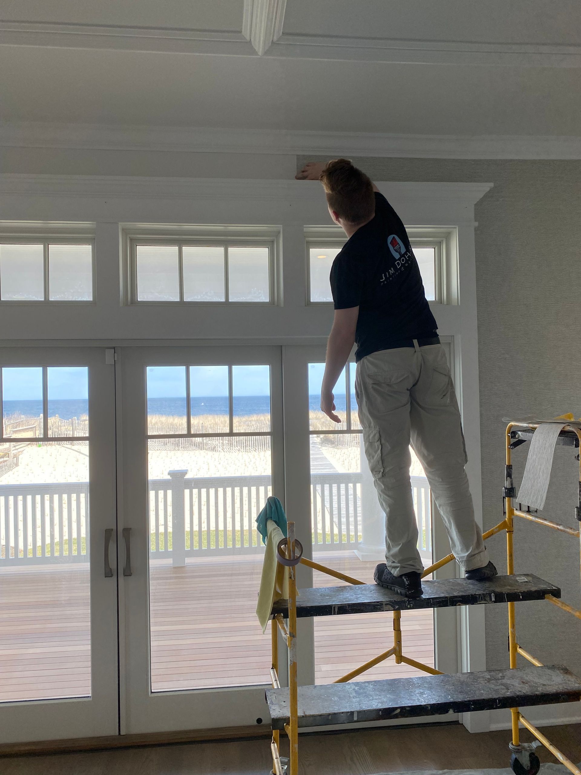 A man is standing on a scaffolding in front of a window.