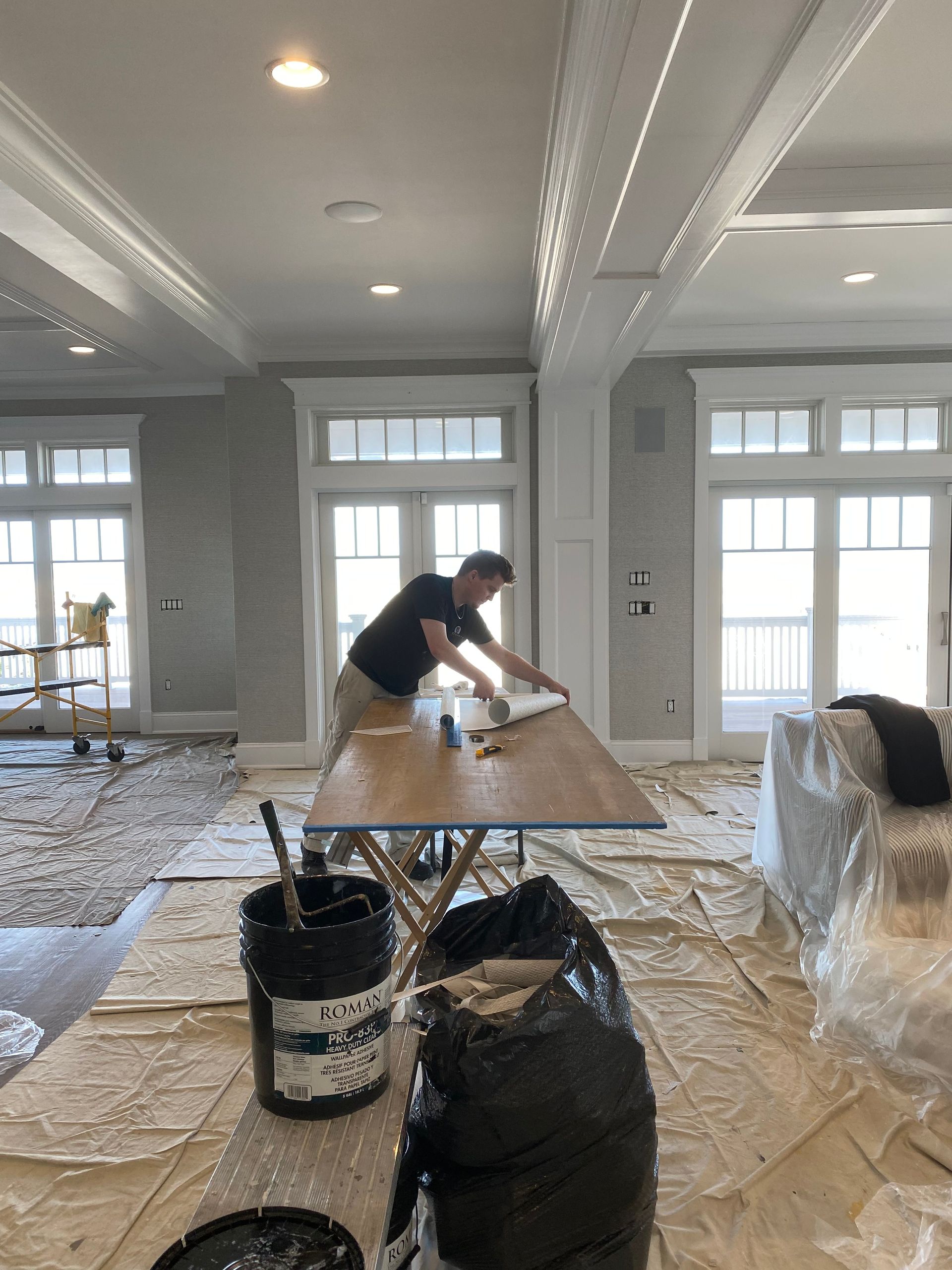 A man is painting a wooden table in a living room.