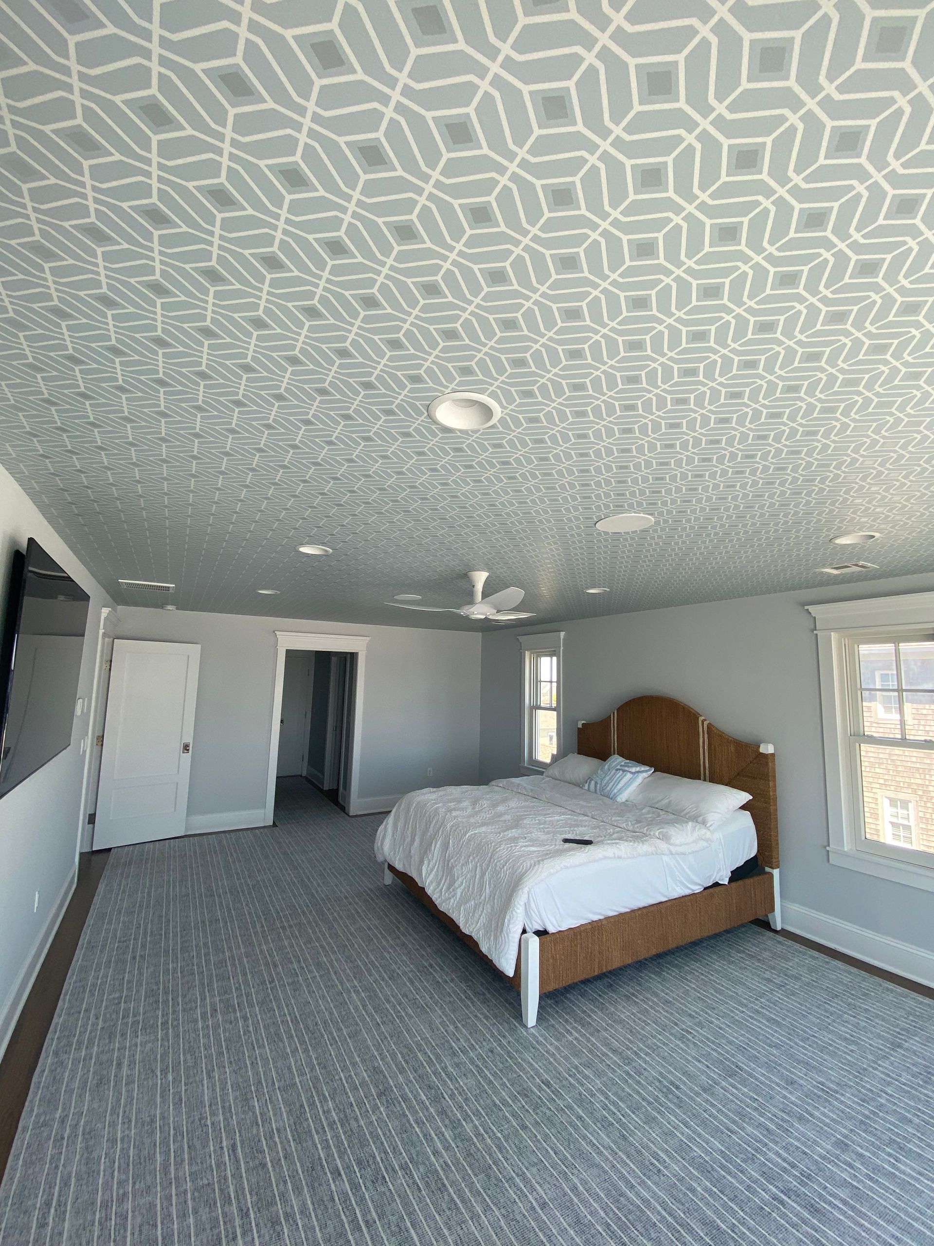 A bedroom with a large bed and a patterned ceiling.
