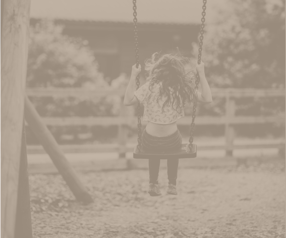 A young girl is sitting on a swing in a park.
