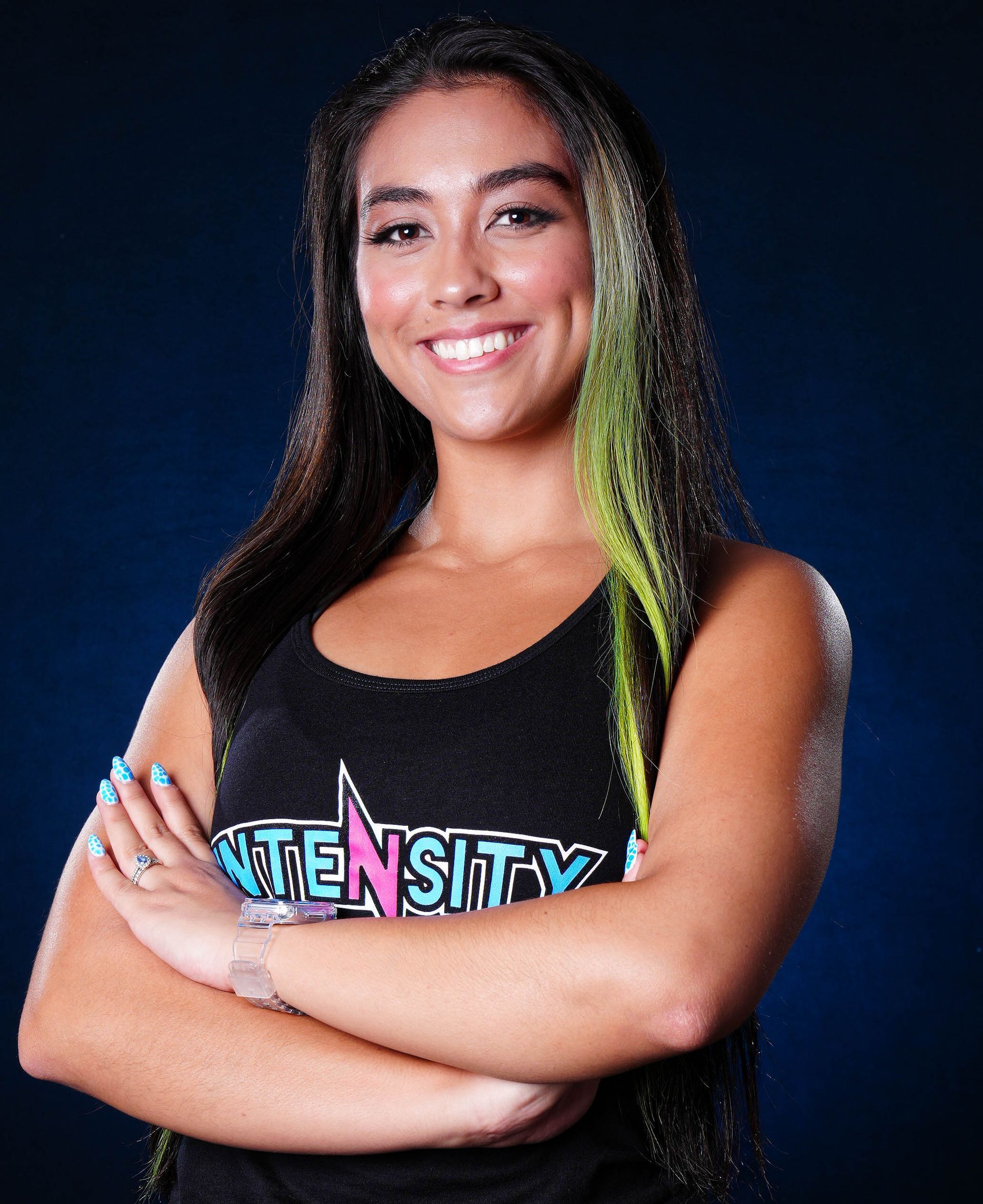 A woman with green hair is wearing a black tank top with the word intensity on it.