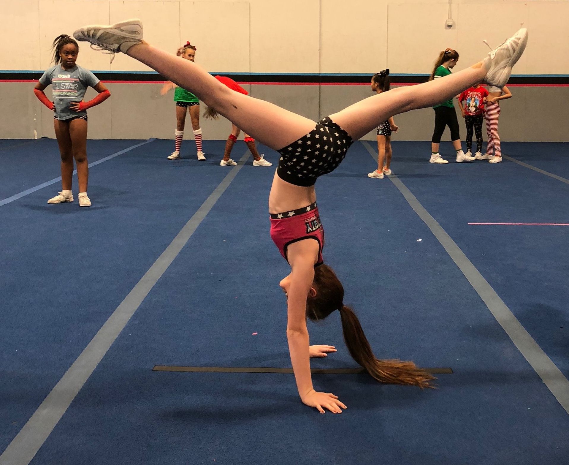 A girl is doing a handstand on a blue mat