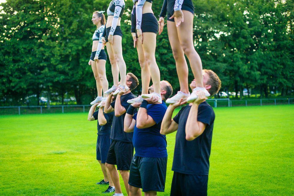 A group of cheerleaders are doing a trick on a field.