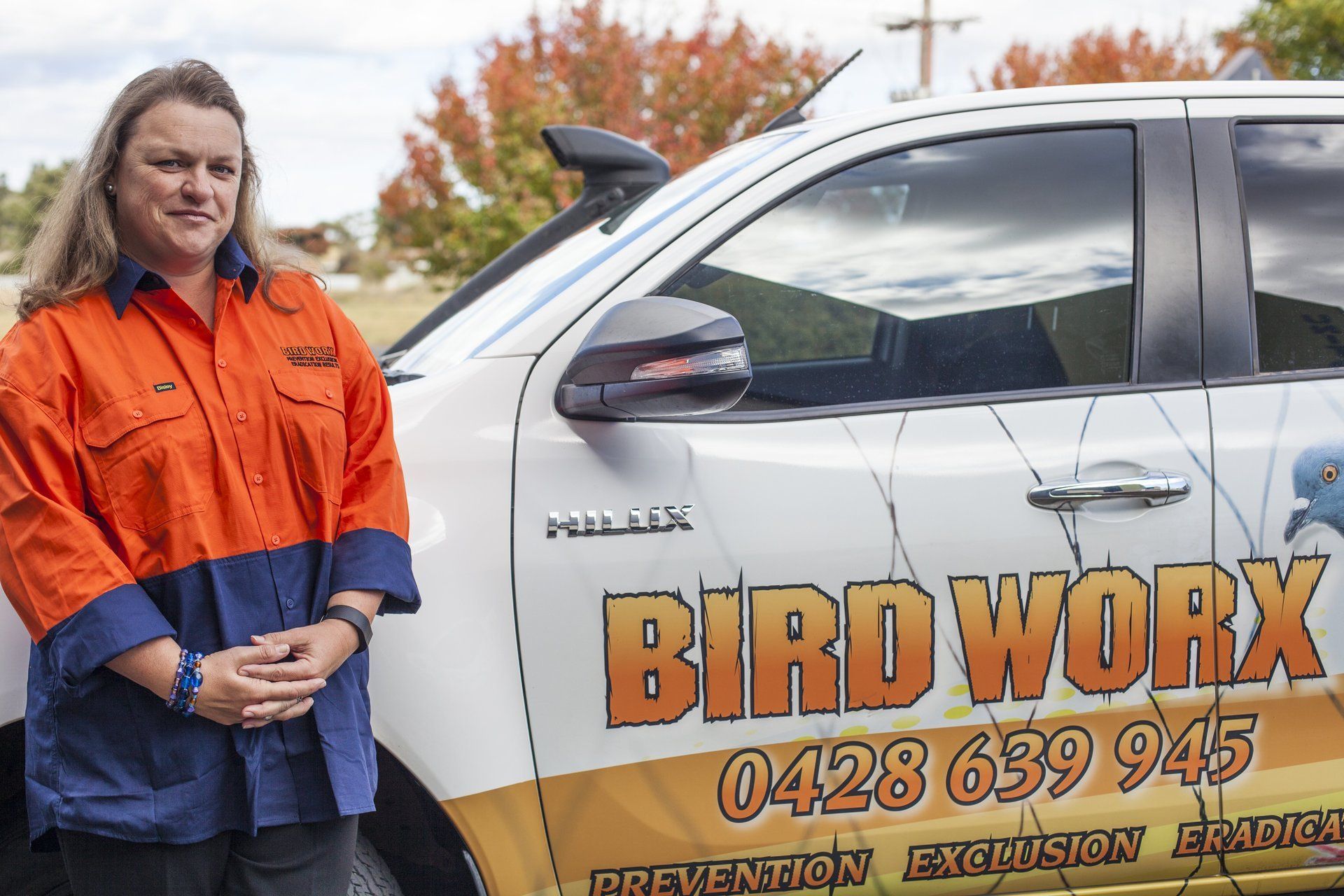 A woman is standing in front of a bird work truck