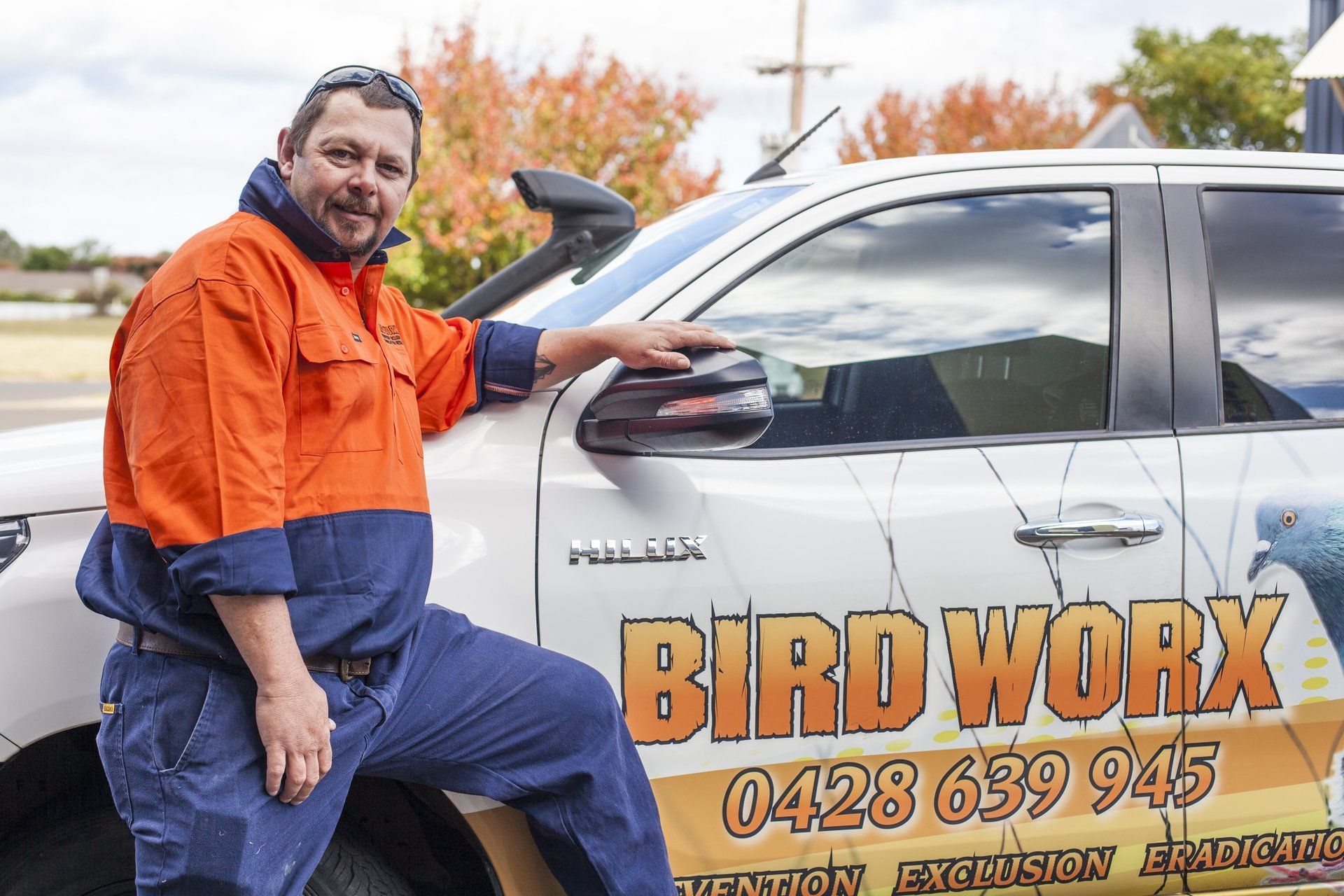 A man is standing next to a bird work truck