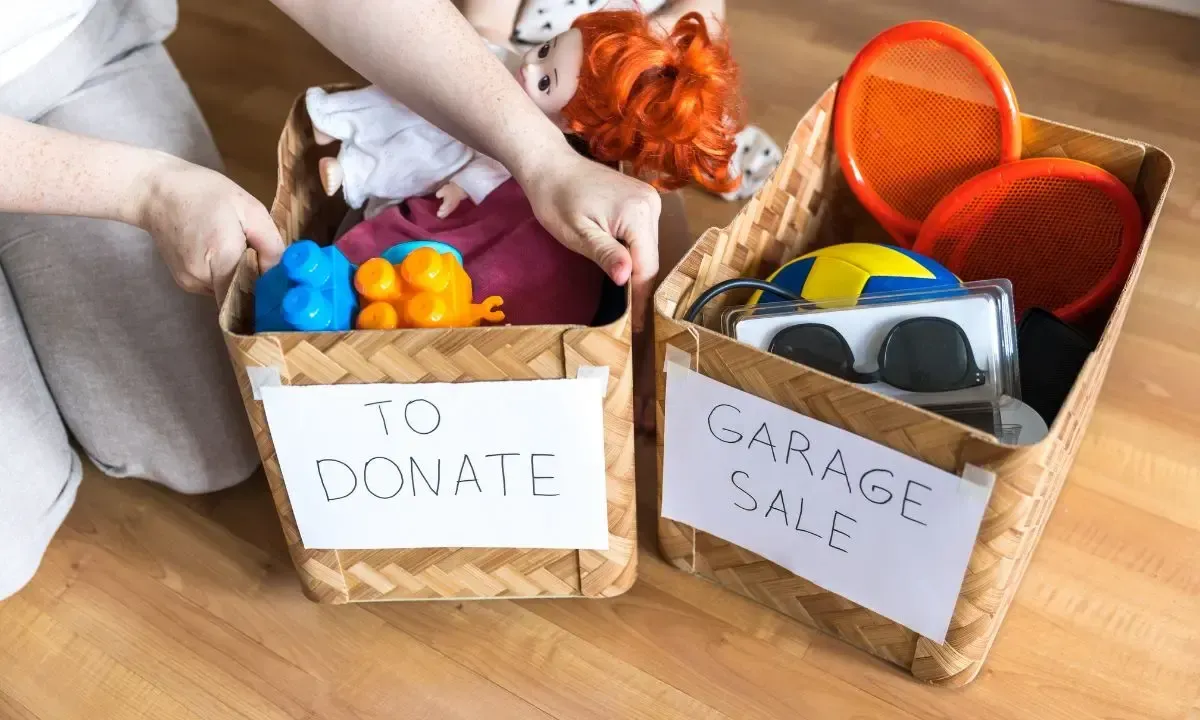 a child is putting toys in a basket for a garage sale .