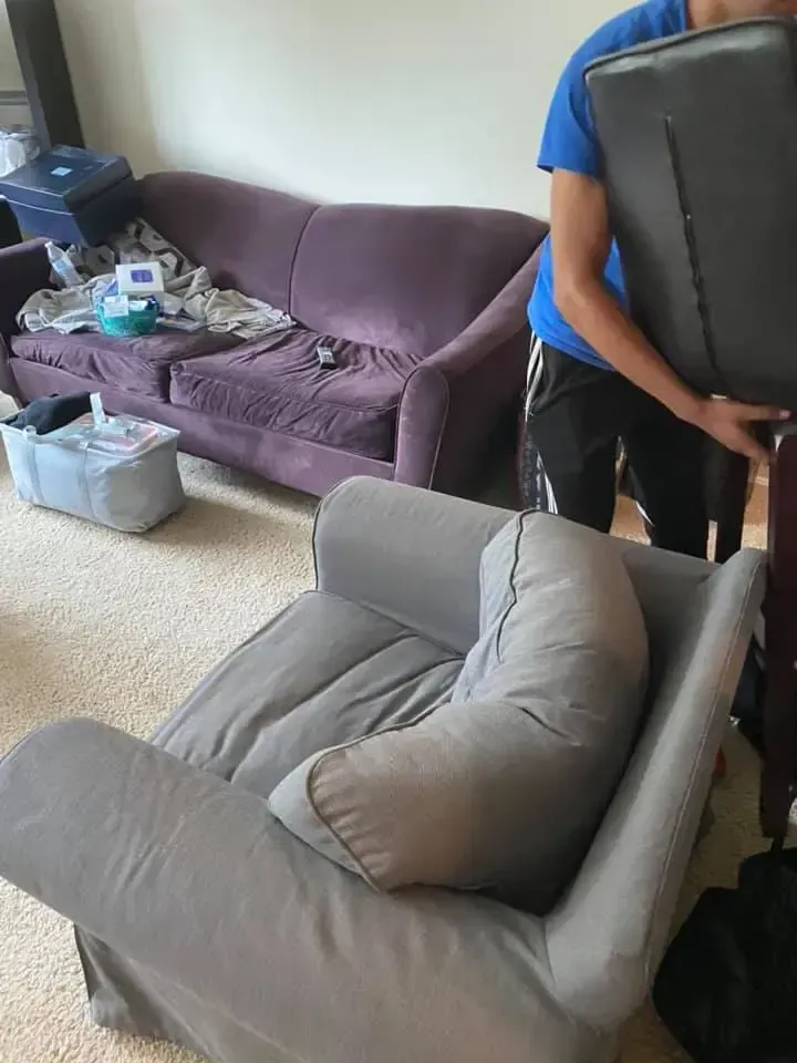 a man is carrying a couch and a chair in a living room .
