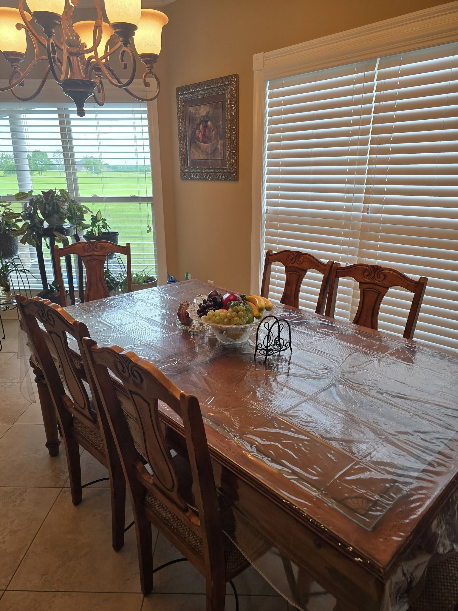 Dining room with a long wooden table set for a meal; chairs and a chandelier visible.