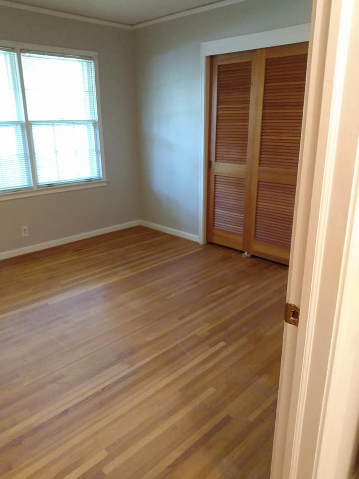 Empty room with hardwood floors, a closed wooden closet door, and a window.
