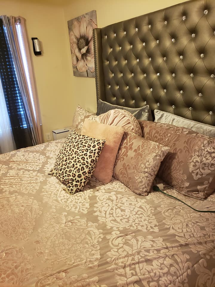 Bedroom with upholstered headboard, patterned bedding, and decorative pillows.