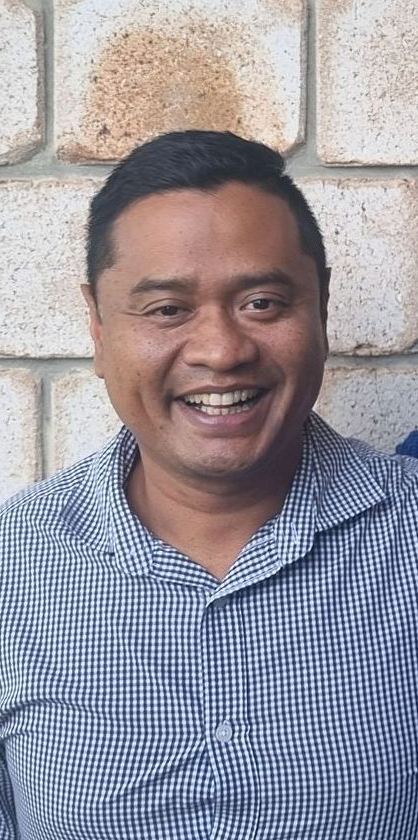 Two men posing for a picture in front of a brick wall