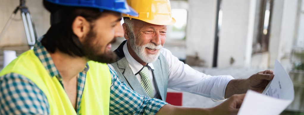 Two men in hard hats are looking at a piece of paper.